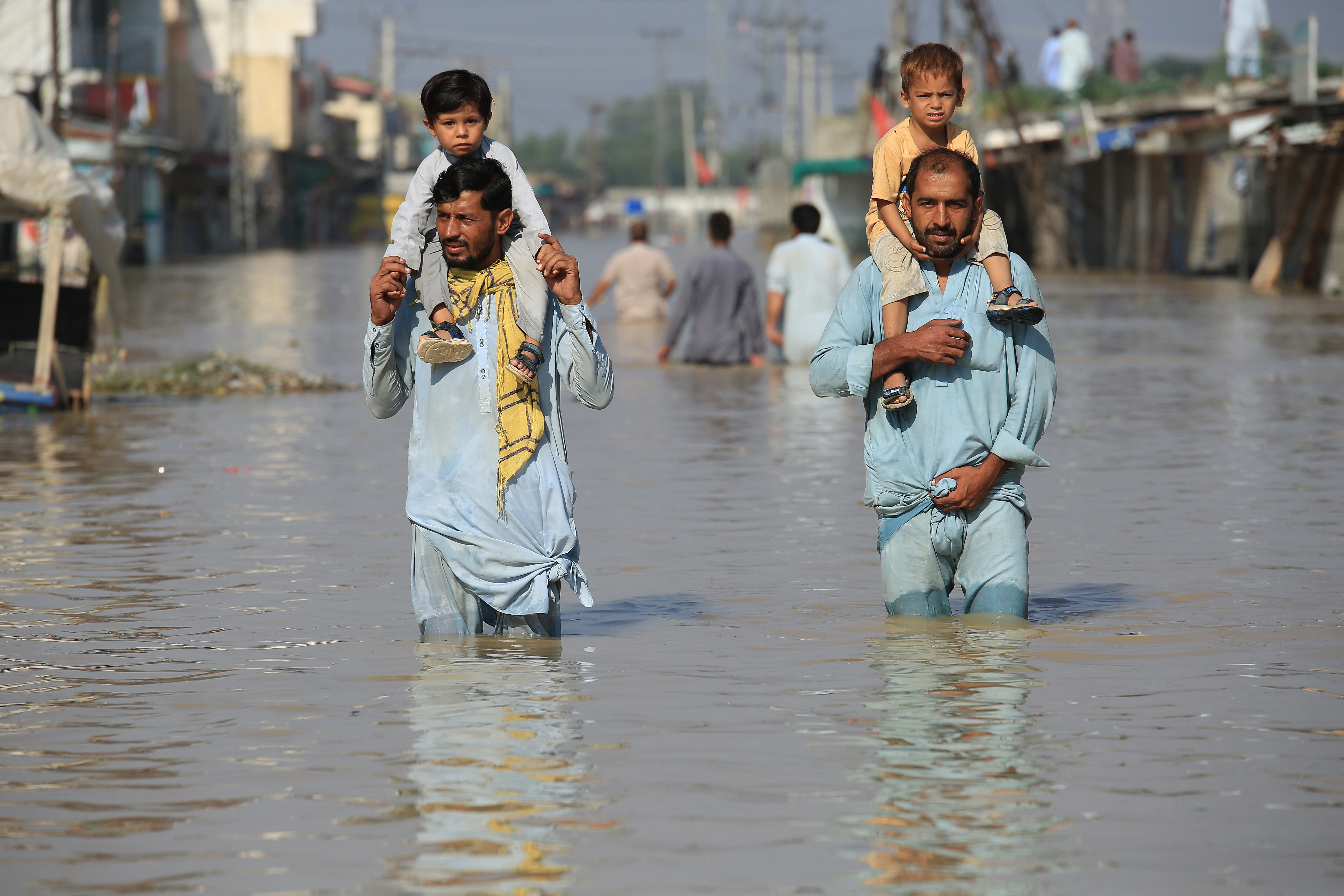 Nowshera (Pakistan), 29/08/2022.- People carrying children wade through a flooded area following heavy rains in Nowshera District, Khyber Pakhtunkhwa province, Pakistan, 29 August 2022. According to the National Disaster Management Authority (NDMA) on 27 August, flash floods triggered by heavy monsoon rains have killed over 1,000 people across Pakistan since mid-June 2022. More than 33 million people have been affected by floods, the country's climate change minister said. (Inundaciones) EFE/EPA/BILAWAL ARBAB