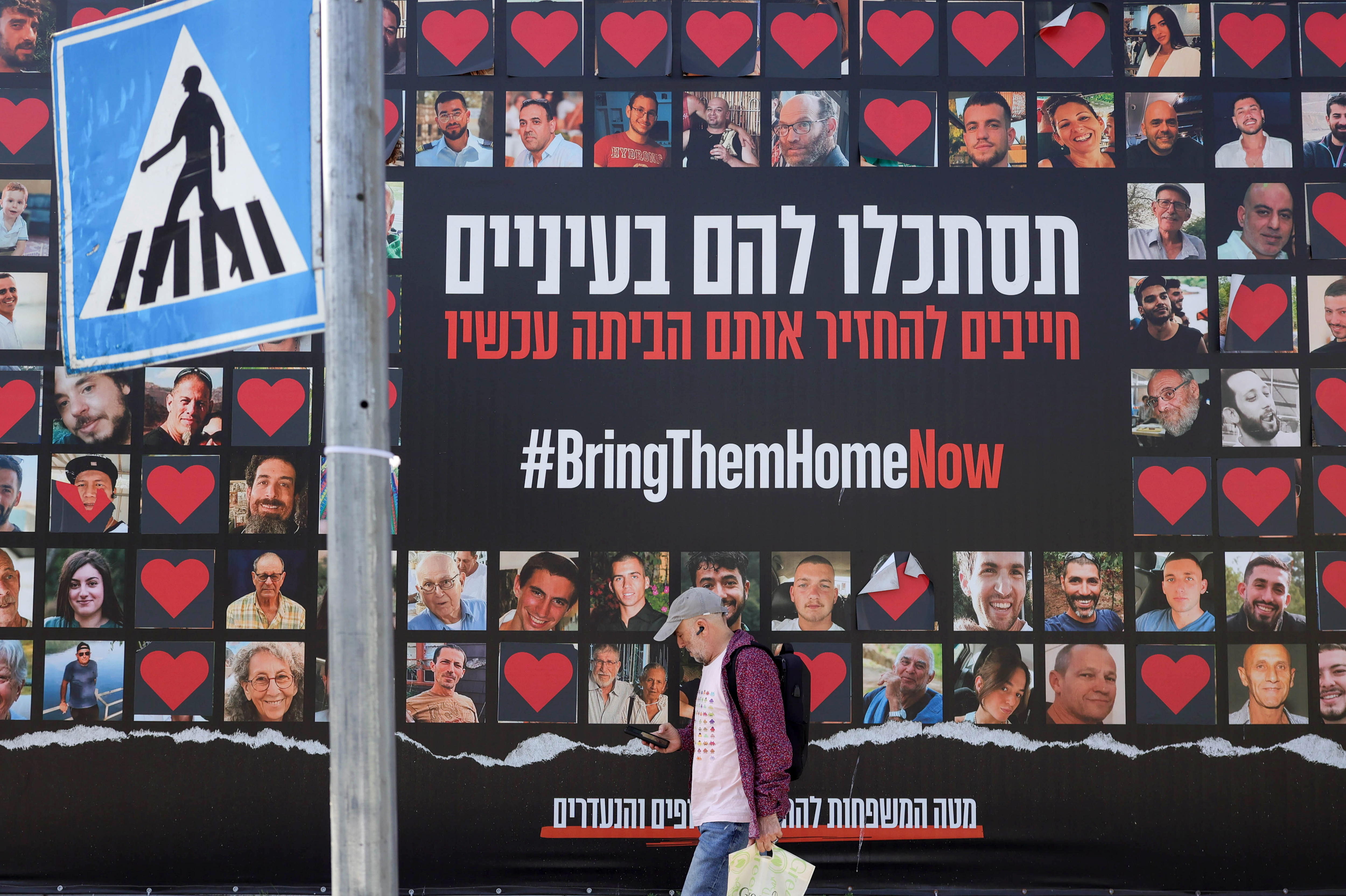 Jerusalem (-), 03/04/2024.- A man walks past a large-scale billboard showing images of Israeli hostages held by Hamas in the Gaza Strip and reading 'Look them in the eyes, we must bring them home now', in Jerusalem, 03 April 2024. According to the Israeli military, 134 Israelis, who were abducted and taken to the Gaza Strip during the 07 October 2023 attacks by Hamas, remain in captivity. Rallies in Israel have been critical of the government's handling of the crisis, demanding the immediate release of all hostages. (Jerusalén) EFE/EPA/ABIR SULTAN
