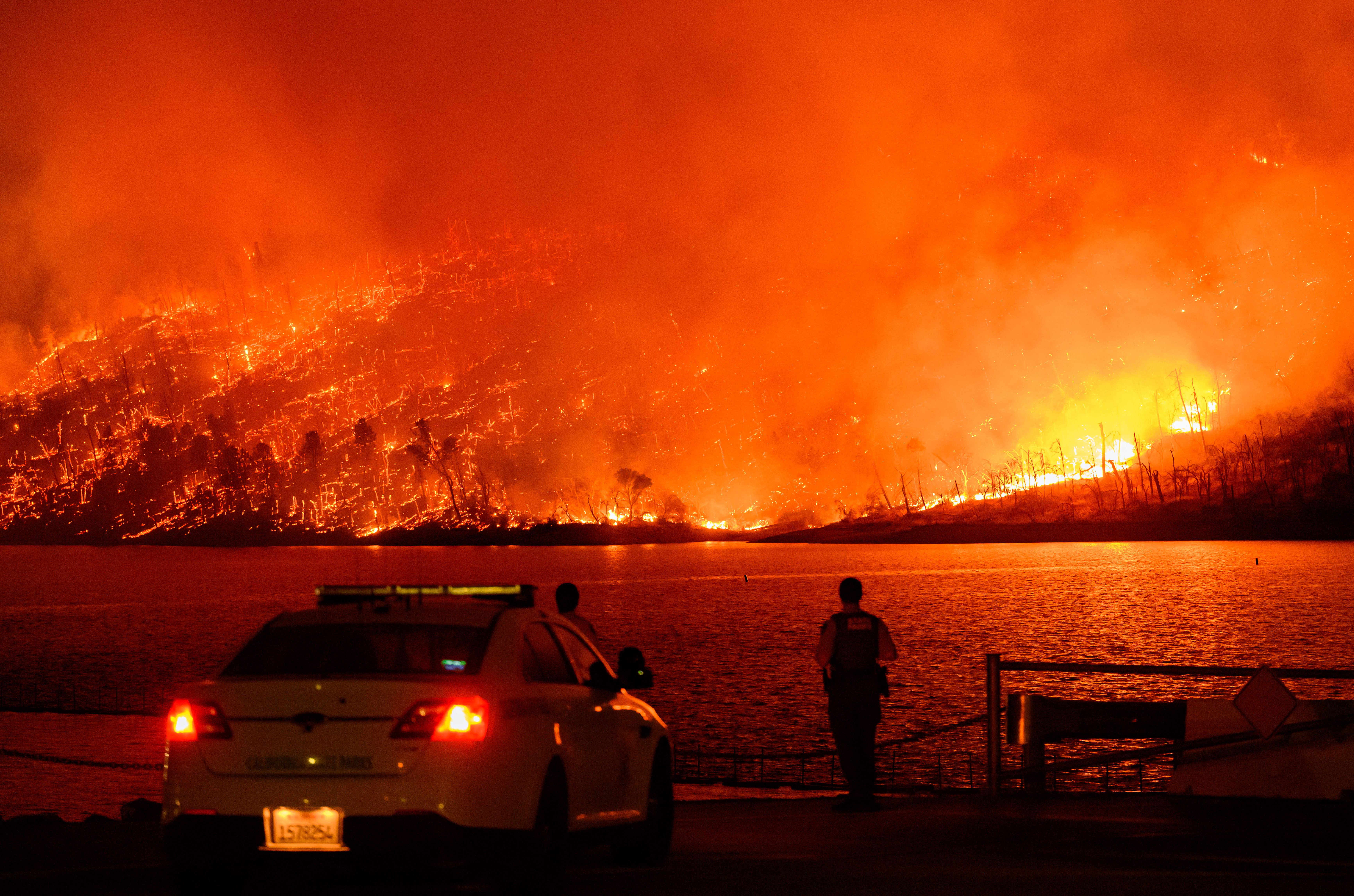 TOPSHOT - Law enforcement members watch as the Thompson fire burns over Lake Oroville in Oroville, California on July 2, 2024.