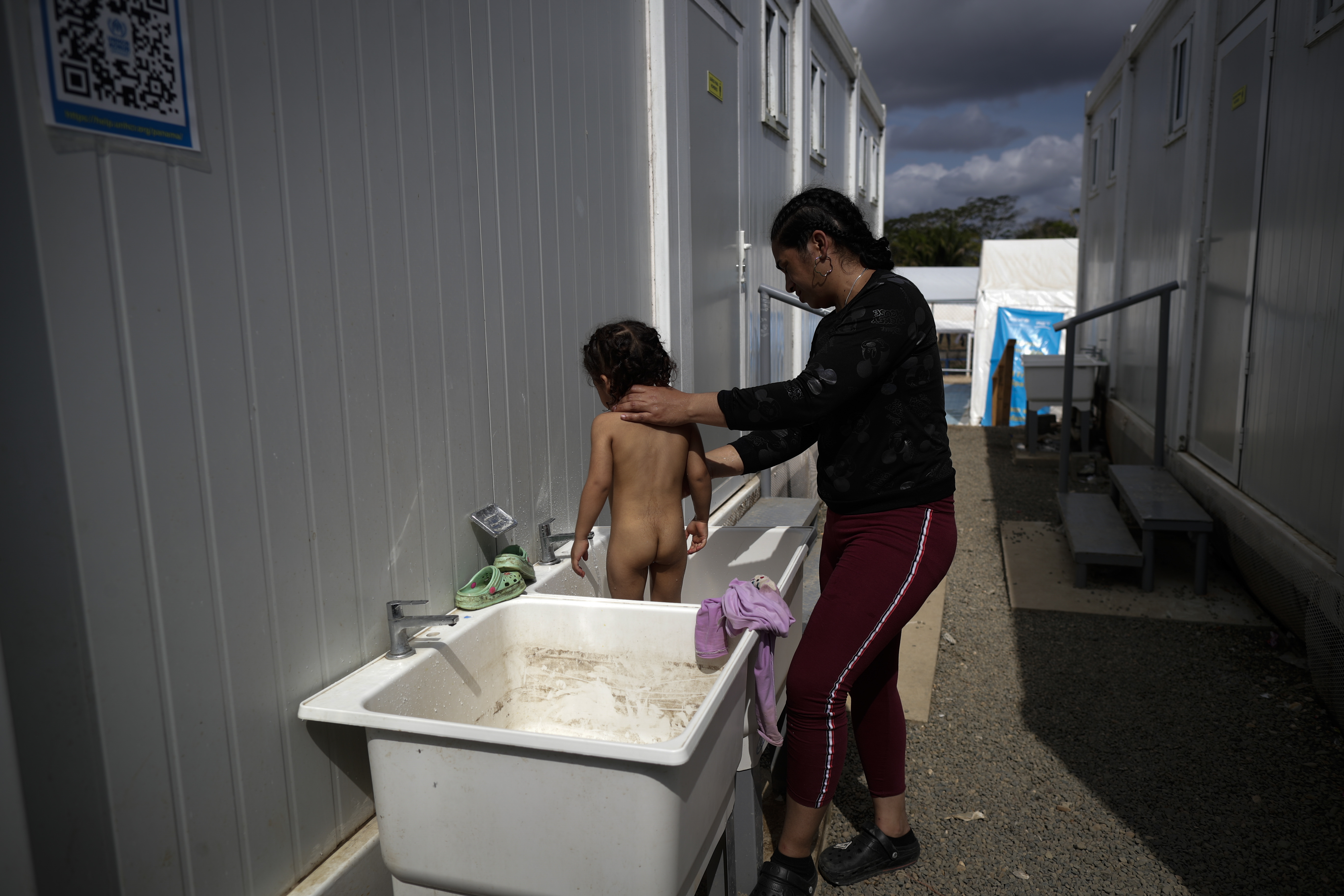 -FOTOGALERÍA- AME4250. BAJO CHIQUITO (PANAMÁ), 21/03/2023.- Una migrante baña a su hijo en la Estación de Recepción Migratoria (ERM) de San Vicente en Metetí (Panamá), el 11 de marzo de 2023. "Guerreros", repiten las madres, hijos guerreros que han aguantado largas caminatas, hambre, sed, el calor, picaduras de insectos, superar ríos y cerros, para sobrevivir a la selva del Darién en su ruta hacia Estados Unidos. Recién salidos de esta selva que hace de frontera natural entre Colombia y Panamá, los migrantes llegan hasta la conocida como Quebrada del León, donde les esperan unas piraguas de indígenas que los descenderán por el casi seco río Tuquesa hasta Bajo Chiquito, una pequeña población emberá donde podrán al fin reposar tranquilos. EFE/ Bienvenido Velasco