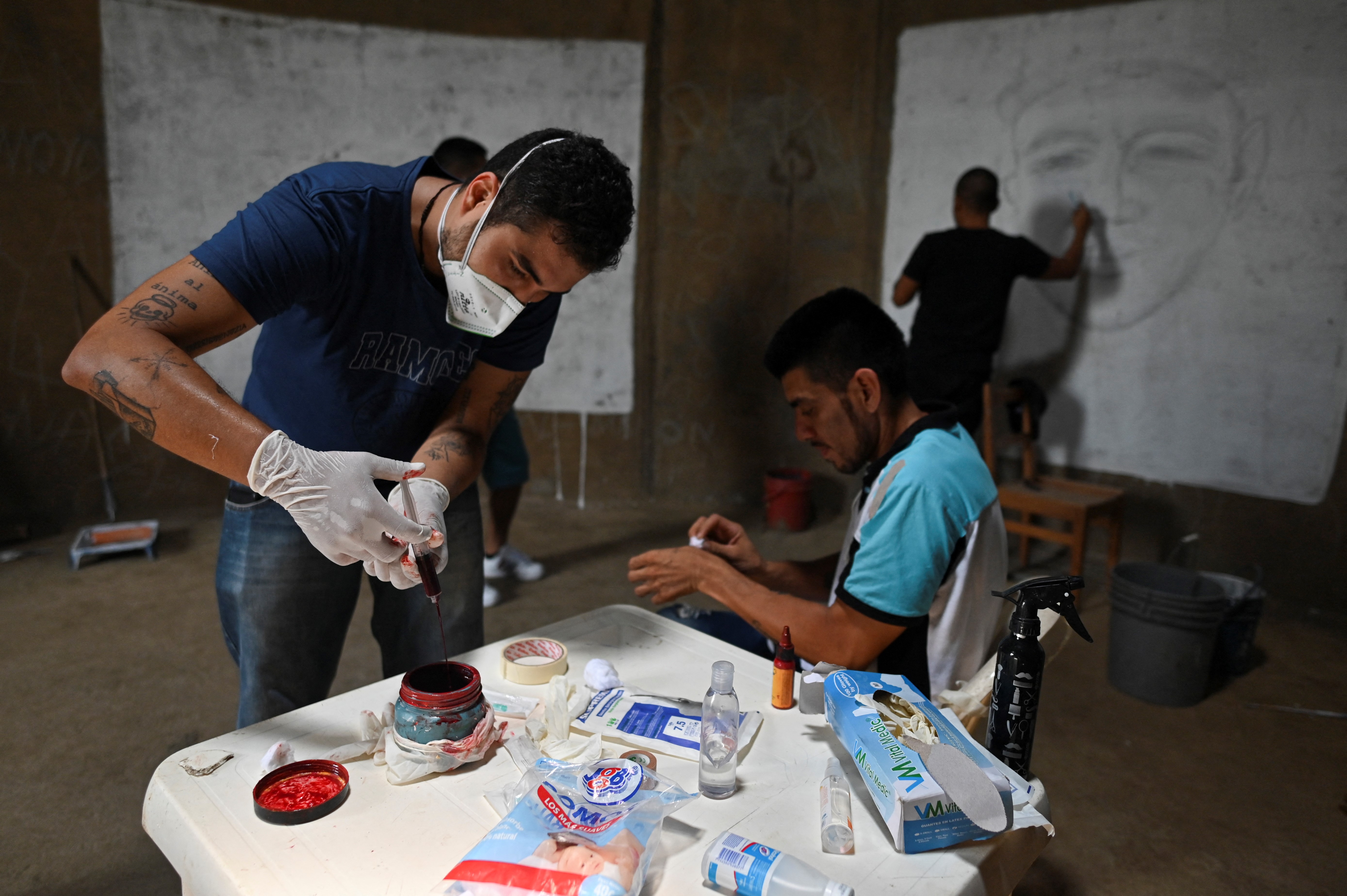 La sangre la combinan con gotas de pigmento para que dure el color. El artista colombiano Julián Castillo pintó un mural del cantante puertorriqueño  René Pérez, Residente, y una paloma de la paz en el barrio Siloé en Cali, el 23 de marzo de 2022, en rechazo a la violencia. 
(Foto por Luis ROBAYO / AFP)