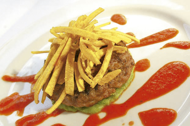 Hamburguesa de ternera sobre puré de arveja con salsa de tomate