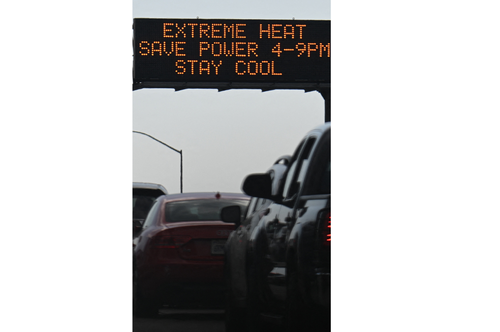 Los vehículos pasan frente a un letrero en la autopista 110 que advierte sobre el calor extremo e insta a la conservación de energía durante una ola de calor en el centro de Los Ángeles, California