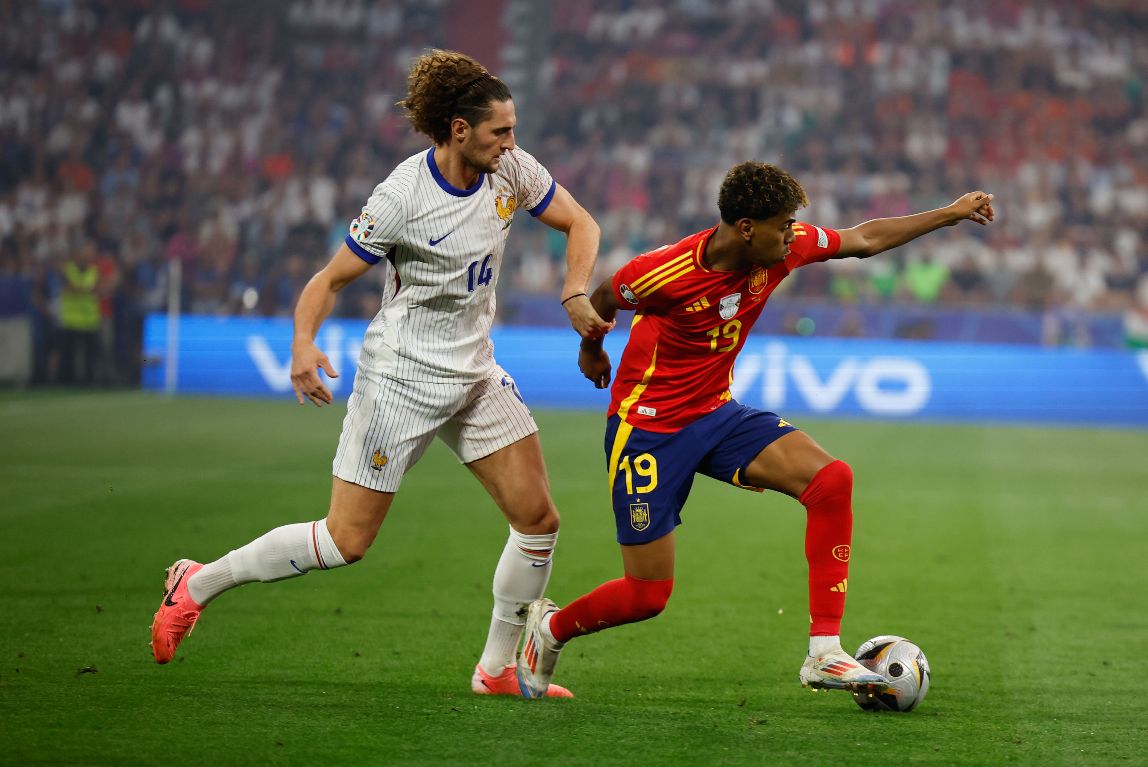 MÚNICH (ALEMANIA), 09/07/2024.- El delantero de la selección española Lamine Yamal (d) juega un balón ante Adrien Rabiot, de Francia, durante el partido de semifinales de la Eurocopa de fútbol que España y Francia disputan este martes en Múnich. EFE/Alberto Estévez