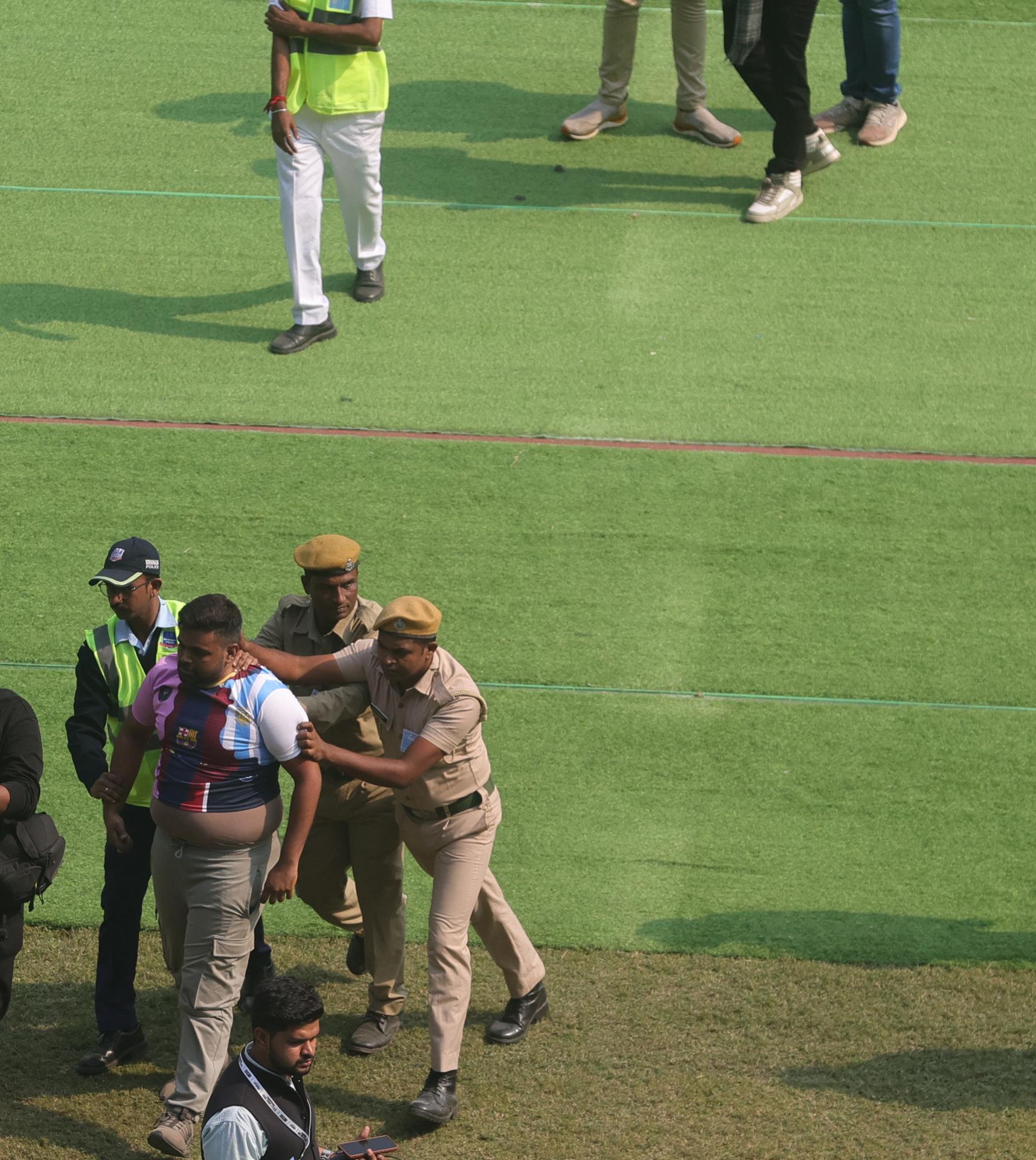 KOLKATA (India), 13/12/2025.- Police officers try to stop a fan as bottles and chairs are thrown and hoardings are vandalised at Salt Lake Stadium in Kolkata, 13 December 2025. Following Messi’s brief five-minute appearance, unrest broke out among fans who had paid a significant amount but were unable to see the Argentine football legend. EFE/EPA/PIYAL ADHIKARY
