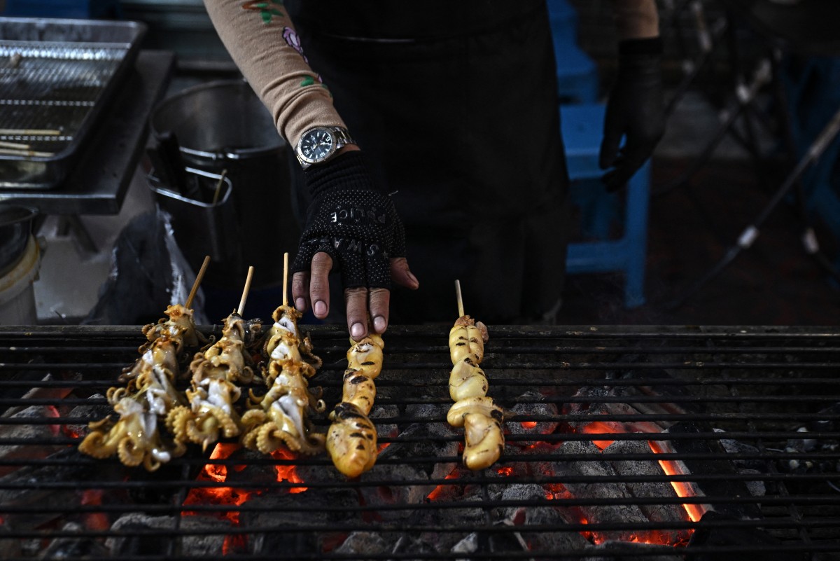This photo taken on April 29, 2026 shows street food vendors grilling seafood in Chinatown in Bangkok.