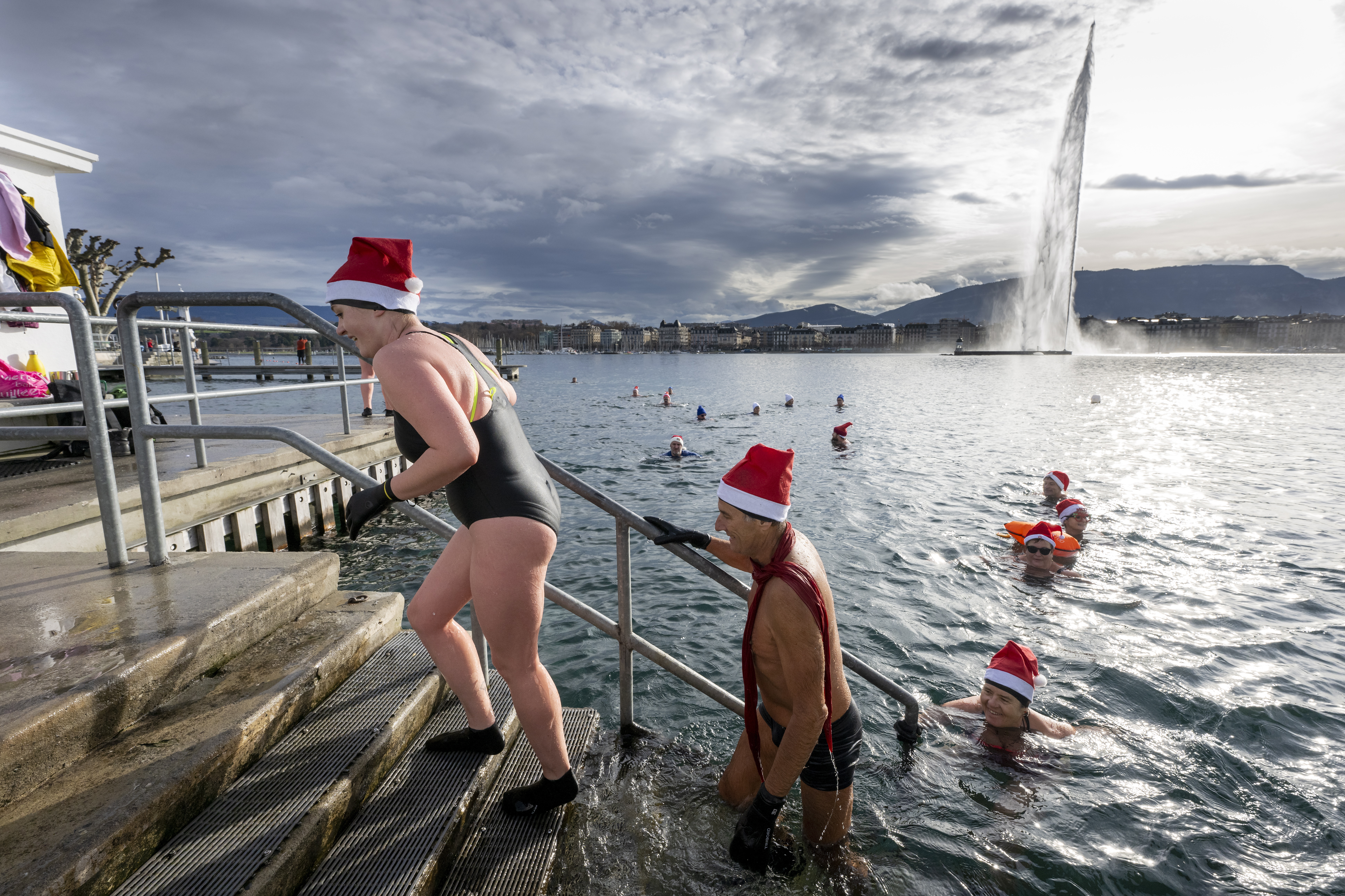Geneva (Switzerland), 24/12/2022.- Swimming enthusiasts wear Santa hats as they brave the nine degrees Celsius 'warm' water by the famous water fountain 'Le Jet d'Eau' in Lake Leman at the 'Bains des Paquis' in Geneva, Switzerland, on Christmas Eve, 24 December 2022. (Suiza, Ginebra) EFE/EPA/MARTIAL TREZZINI