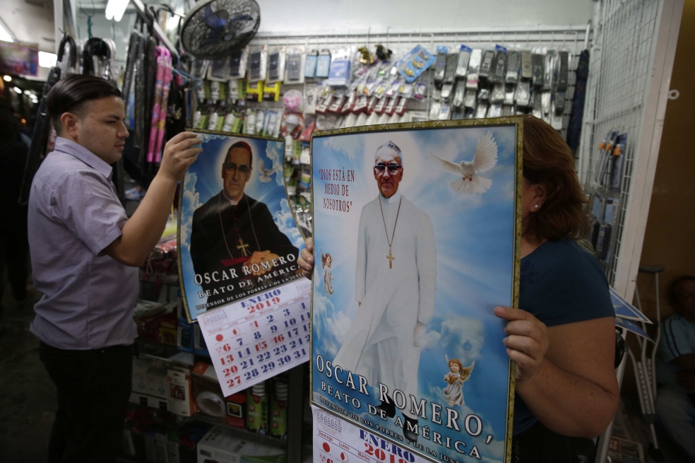 Varias personas sostiene calendarios con la imagen de monseñor Óscar Arnulfo Romero en un comercio de El Salvador.