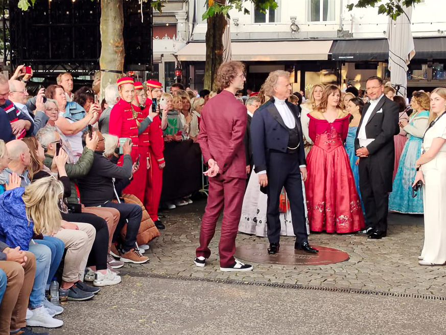André Rieu inicia su camino hacia el escenario al lado de su orquesta. Su hijo Pierre lo acompaña.