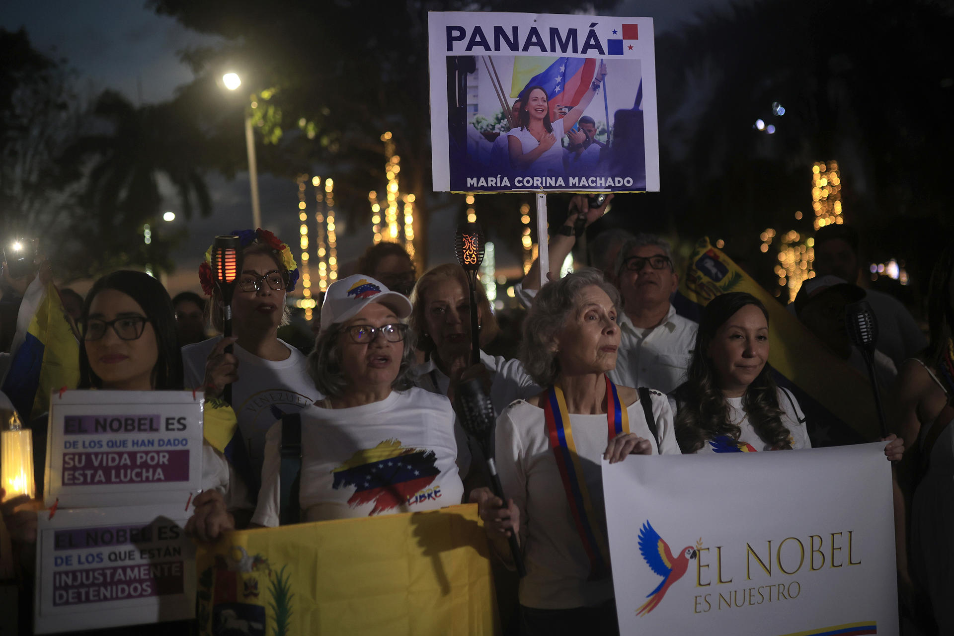 AME6424. CIUDAD DE PANAMÁ (PANAMÁ), 06/12/2025.- Personas sostienen carteles durante la marcha "por la paz y la libertad" en Venezuela este sábado, en Ciudad de Panamá (Panamá). Decenas de venezolanos se sumaron en Panamá a las marchas globales "por la paz y la libertad" en Venezuela convocadas el jueves por la líder opositora y exdiputada del país sudamericano María Corina Machado. EFE/ Bienvenido Velasco
