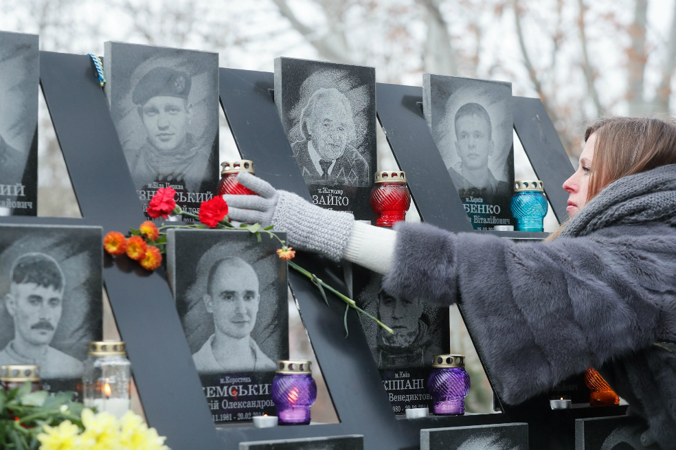 Varias personas depositan flores sobre el monumento a los "héroes de la Centuria Celestial", como se conoce al centenar de víctimas de los violentos enfrentamientos entre los manifestantes y la policía antidisturbios en febrero de 2014. / EFE