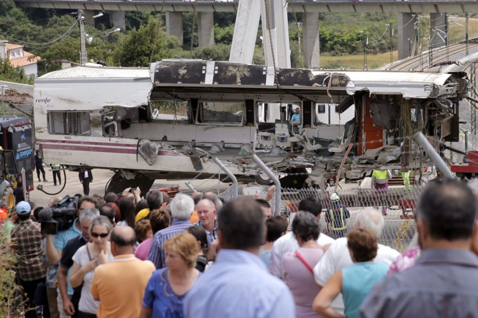 Un grupo de personas contempla las labores de retirada de uno de los vagones del tren Alvia procedente de Madrid que se descarriló  en Santiago de Compostela./ EFE
