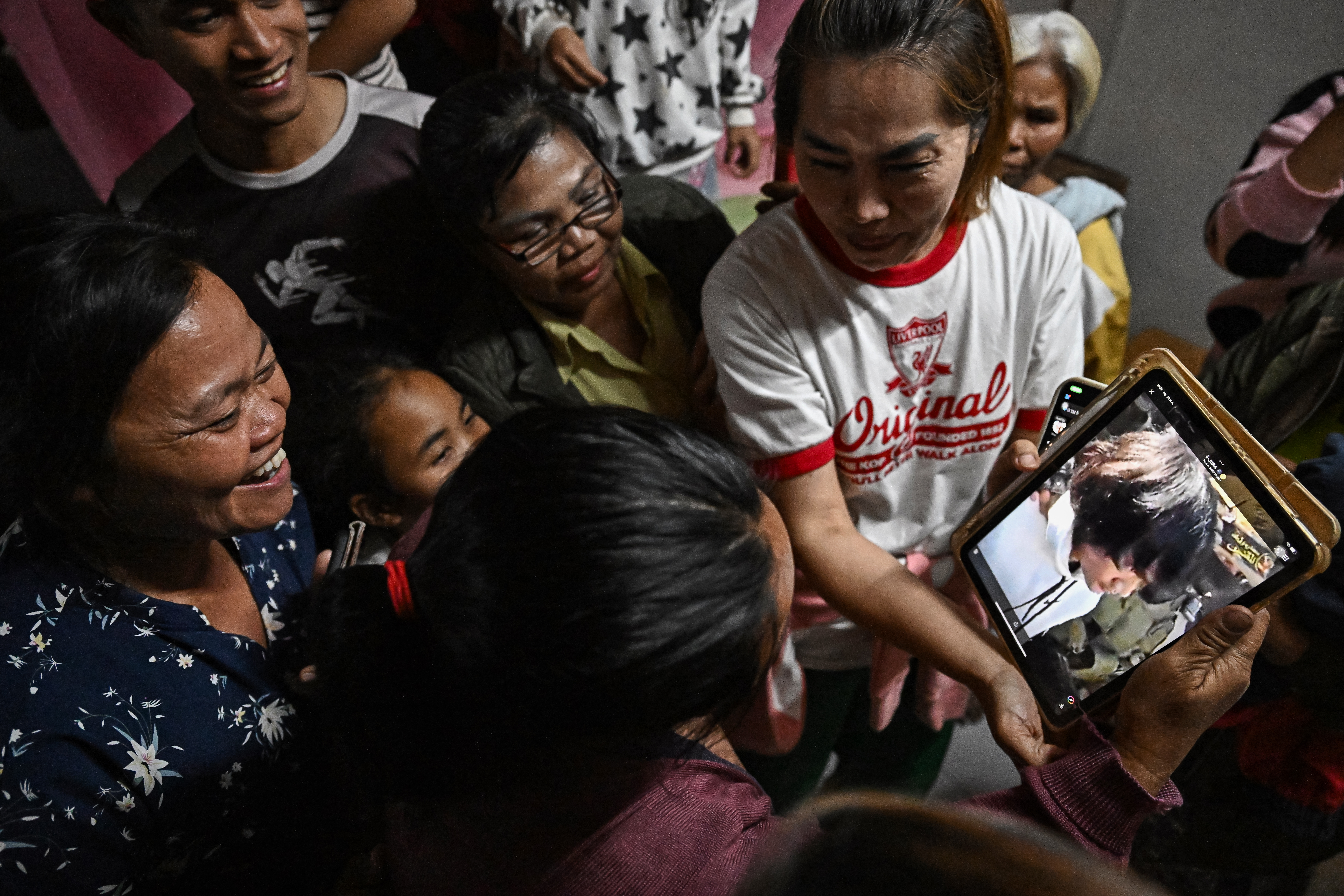 Wiwwaeo Sriaoun (izq.), la madre del trabajador agrícola tailandés Watchara Sriaoun, que estuvo secuestrado en Gaza, reacciona al recibir una imagen de su hijo (der.) siendo liberado, en su casa en la provincia de Udon Thani, en el noreste rural de Tailandia, el 30 de enero de 2025.