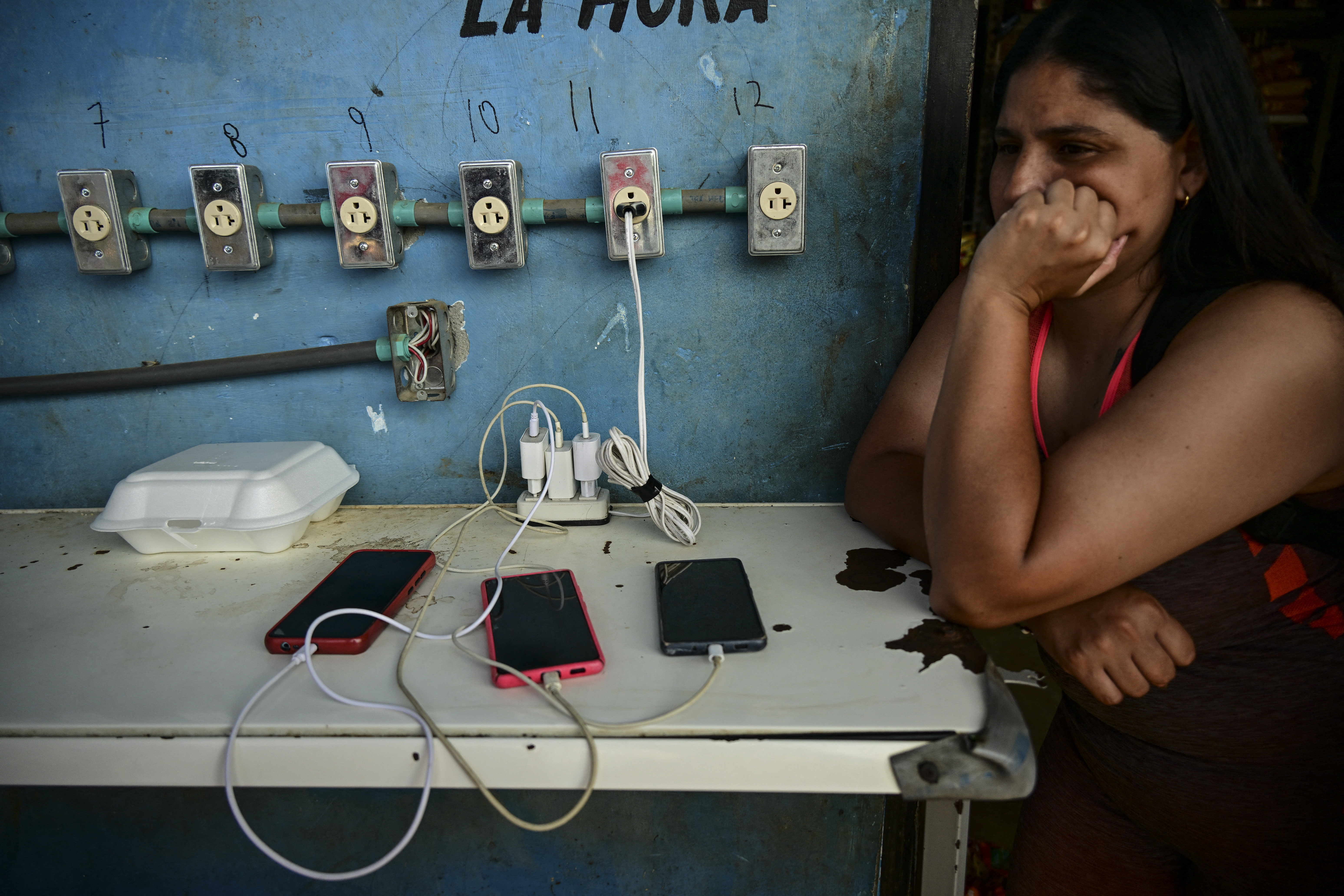 A migrant charges her phone while waiting for a bus to take her to the Costa Rica border in the Reception Center for Migrant Care in Lajas Blancas, in the jungle province of Darien, Panama on June 27, 2024.