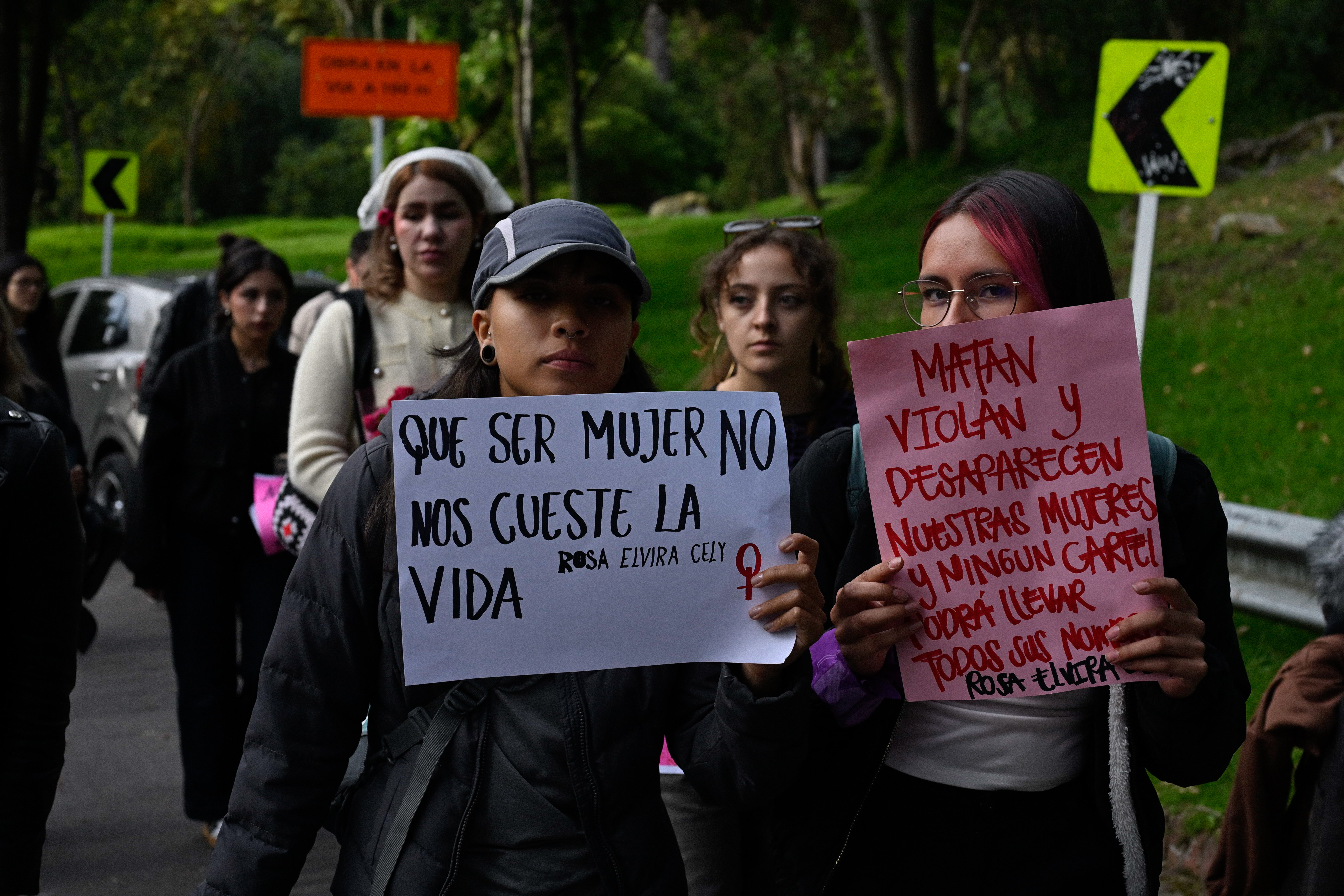 Dos jóvenes marchan con carteles, en la subida al jardín conmemorativo.