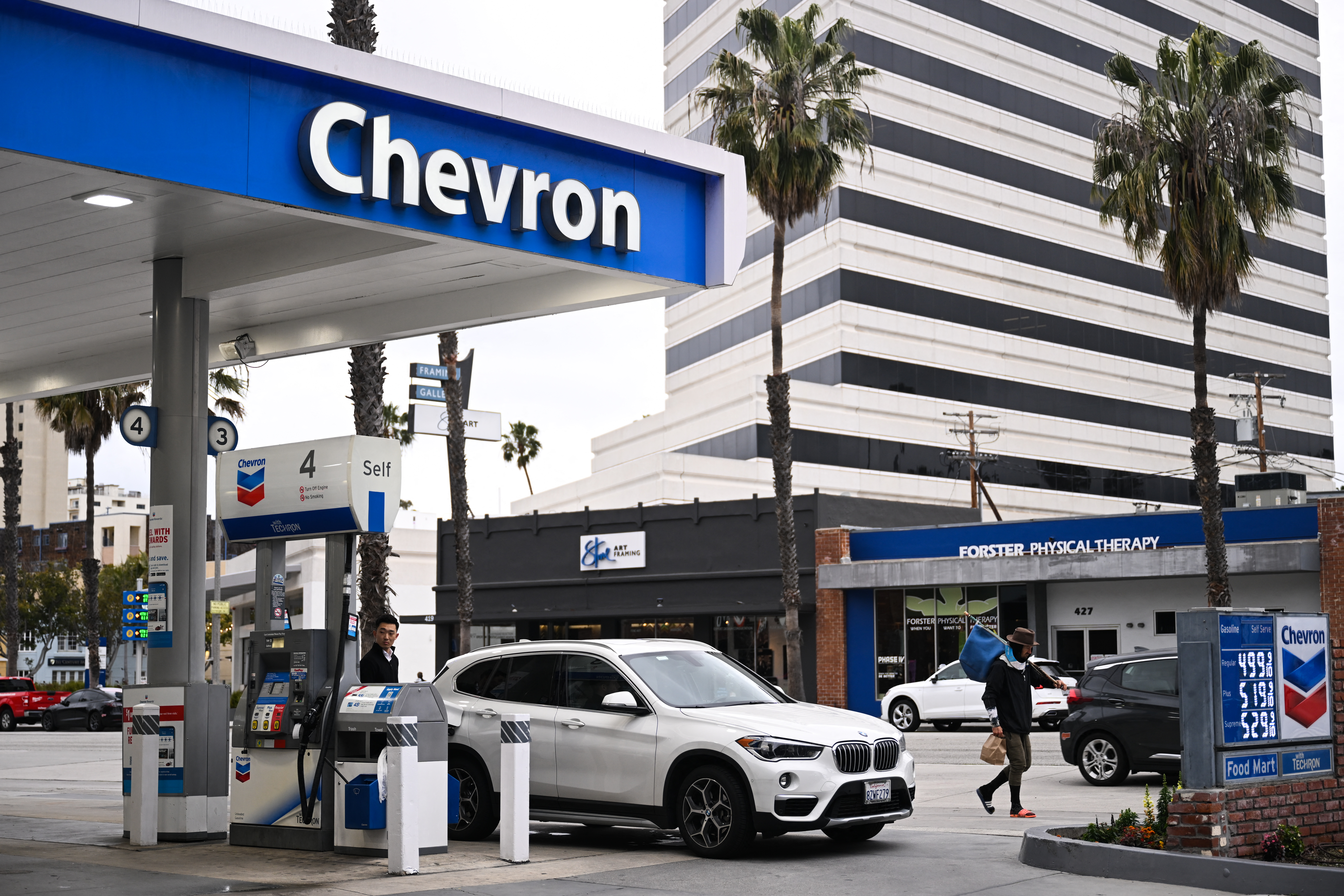 (FILES) A customer pumps gasoline into a BMW vehicle at a Chevron gas station in Santa Monica, California on March 20, 2023.