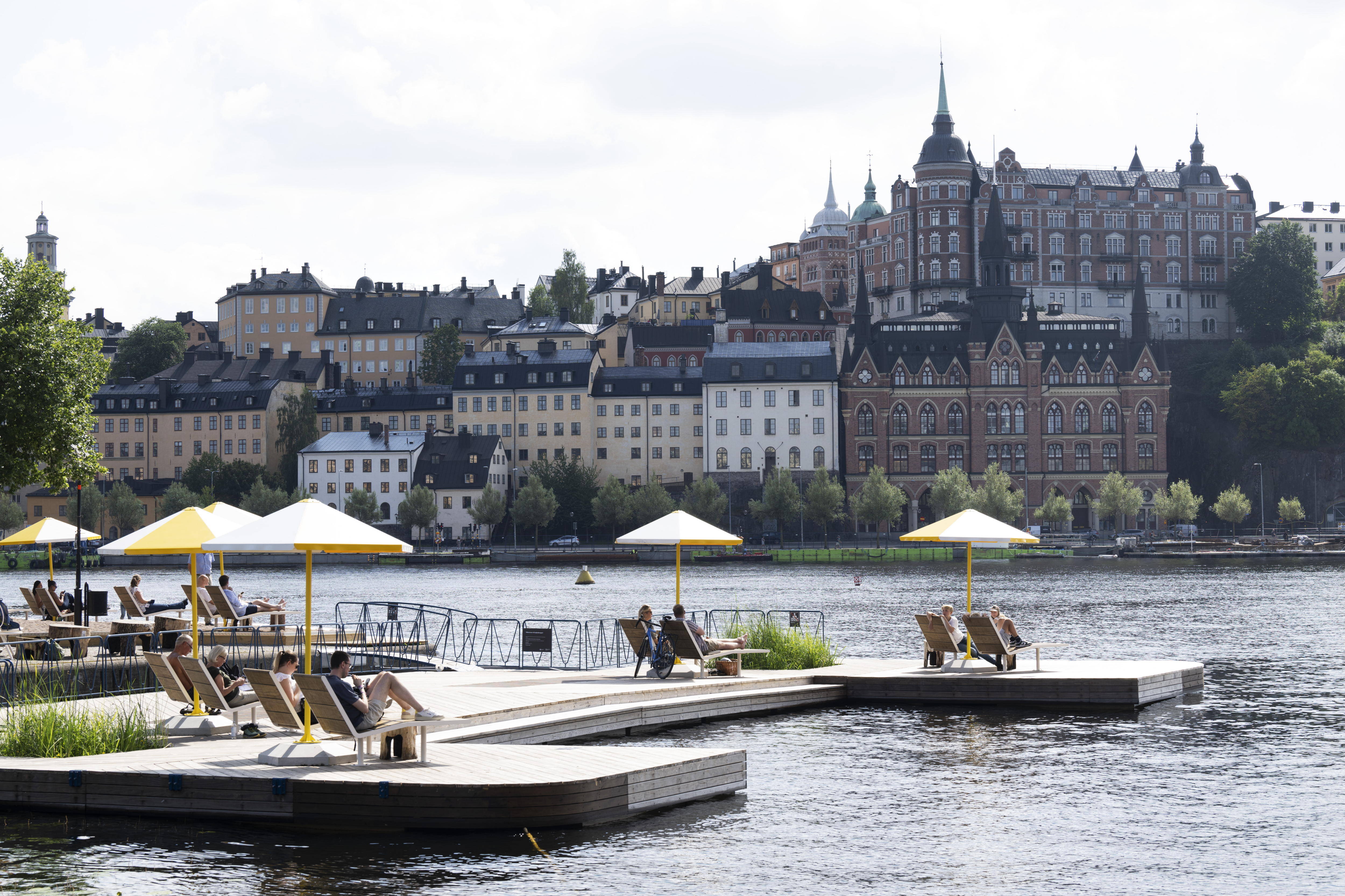 Stockholm (Sweden), 05/08/2024.- People enjoy the warm and summer weather under parasols at the latest addition of viewpoints along the capital's quays, in Stockholm, Sweden, 05 August 2024. The so-called 'Kajbalkongen' is located at Riddarholmen with a view of Lake Malaren and Sodermalm district. (Suecia, Estocolmo) EFE/EPA/FREDERIK SANDBERG SWEDEN OUT
