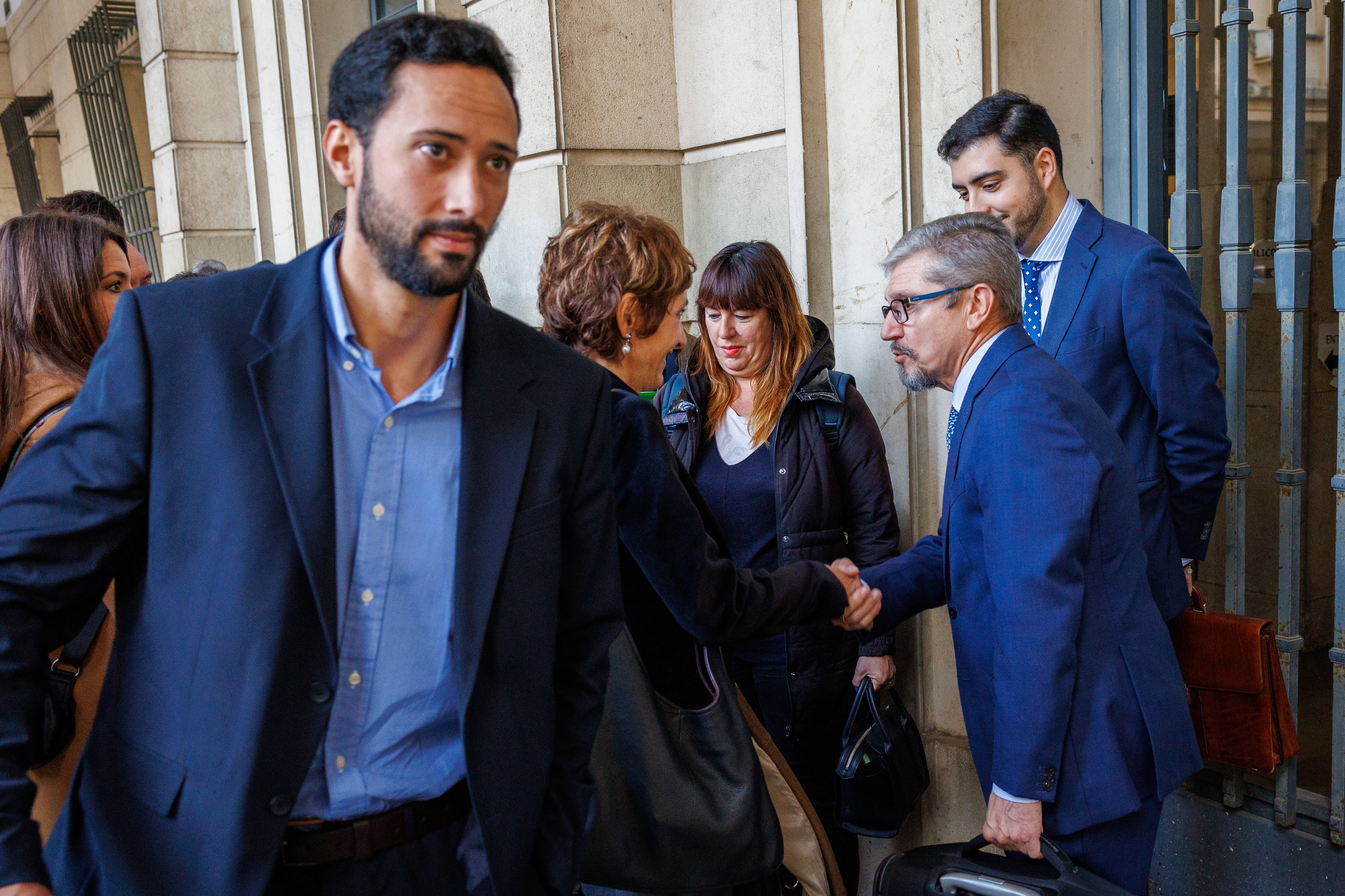 SEVILLA, 21/11/2023.- El rapero José Miguel Arenas Beltrán, más conocido como Valtònyc (i) abandona la sede judicial mientras su abogada, Isabel Elbal (c) y el letrado de la Asociación Unificada de la Guardia Civil, Mariano Casado (d) se dan la mano tras salir del juicio celebrado hoy martes en la Audiencia de Sevilla en el que ha sido condenado a dos años de prisión por llamar "a matar a un guardia civil" durante un concierto, en una sentencia de conformidad acordada entre las partes durante el juicio y previsiblemente no tendrá que ingresar en prisión. EFE/ Julio Muñoz