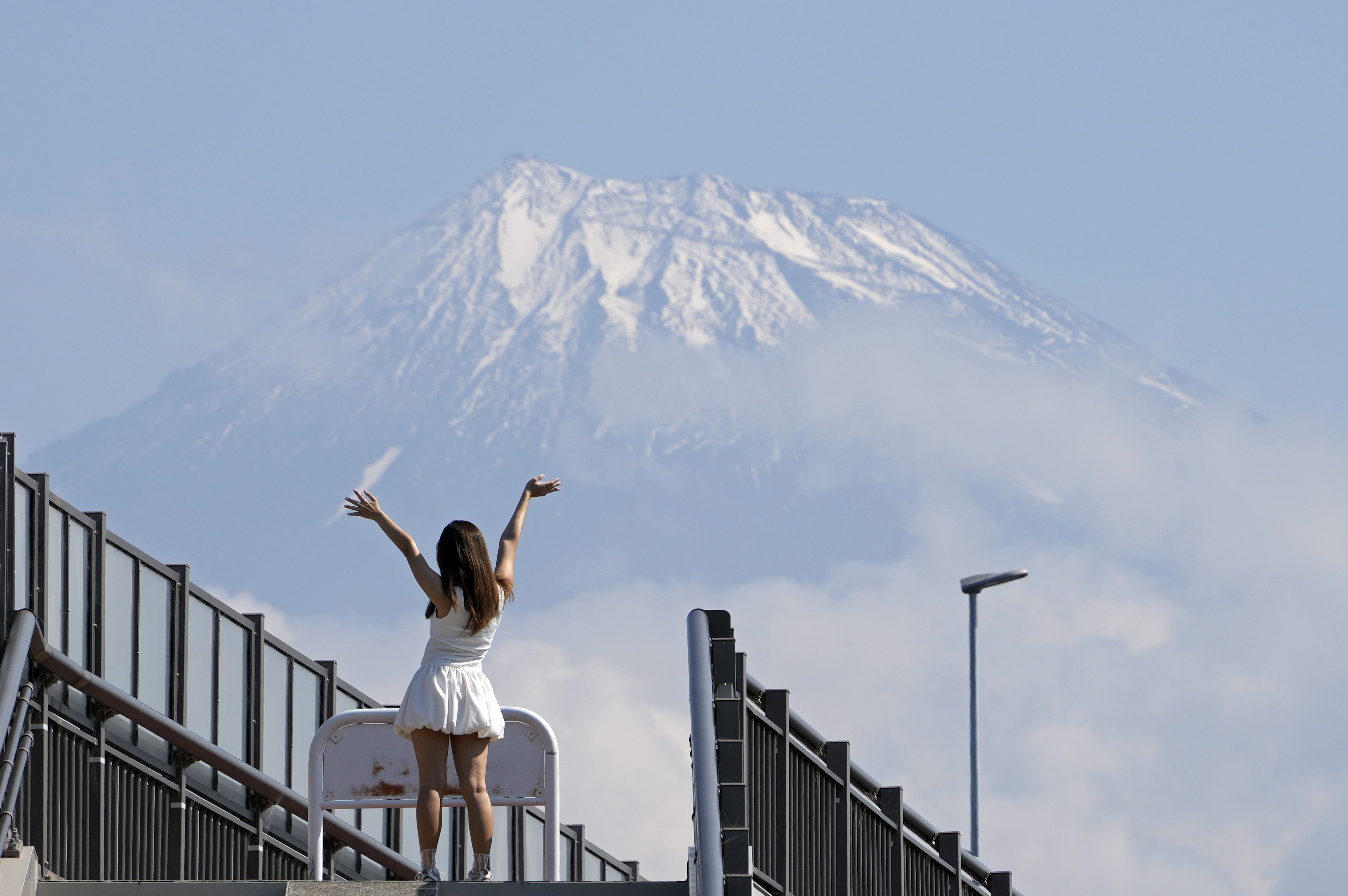 Fuji (Japón), 08/06/2024.- Una turista posa en lo alto de las escaleras que conducen al Fujisan Yumeno Ohashi, o 'Puente del Gran Sueño del Monte Fuji', ya que se ve el Monte Fuji al fondo, en la ciudad de Fuji, prefectura de Shizuoka, este sábado. Este lugar ha ganado popularidad entre los visitantes extranjeros debido a su vista del Monte Fuji, que se ha vuelto viral en las redes sociales. EFE/ Franck Robichon