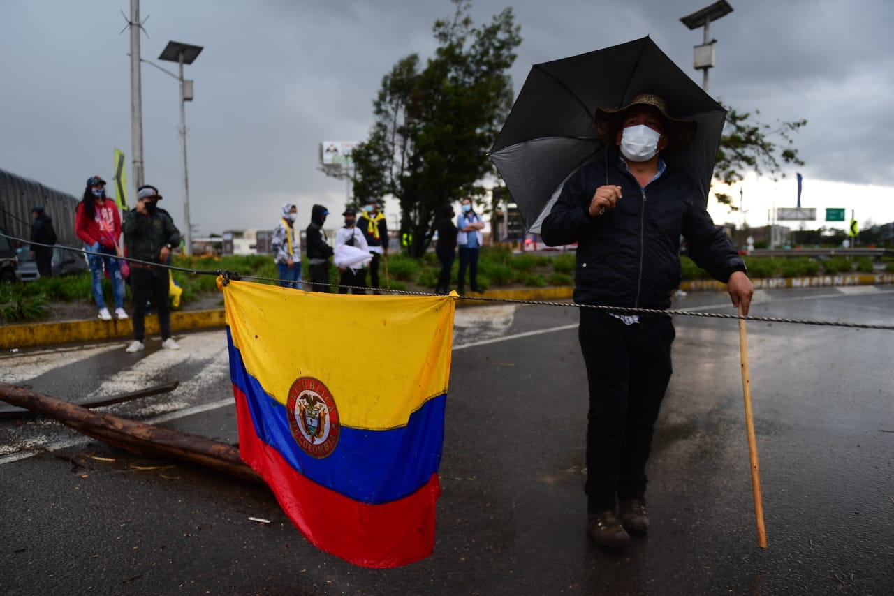 Los manifestantes bloquean las vías con mensajes y banderas de Colombia.