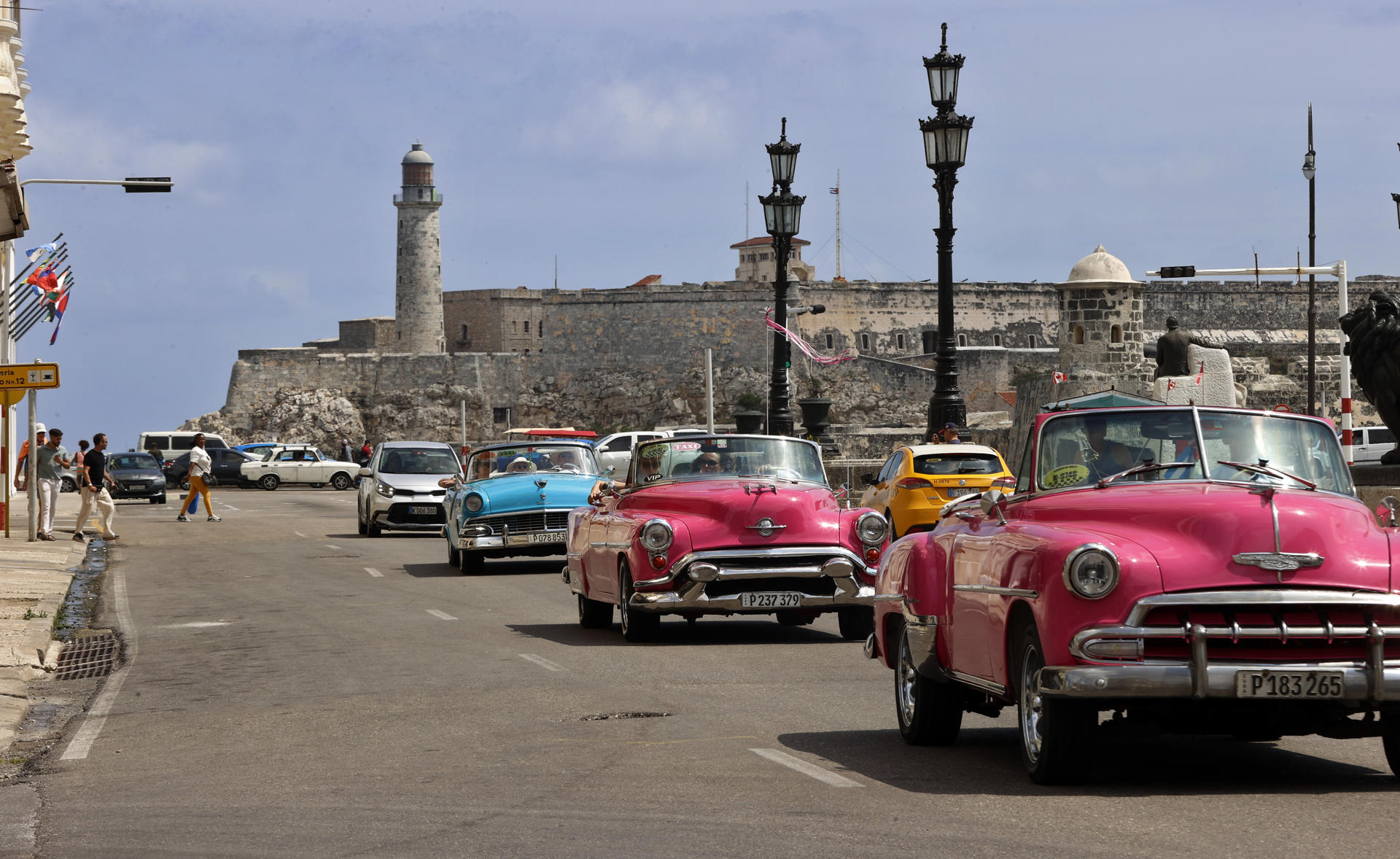 AME2881. LA HABANA (CUBA), 27/04/2025.- Turistas pasean en un auto clásico frente al Castillo del Morro este viernes, en una calle de La Habana (Cuba). El fin de la temporada alta en Cuba ha puesto de nuevo en evidencia que el turismo sigue sin levantar cabeza en una isla que durante décadas tuvo a este sector como motor de la economía y fuente fundamental de divisas. EFE/ Ernesto Mastrascusa
