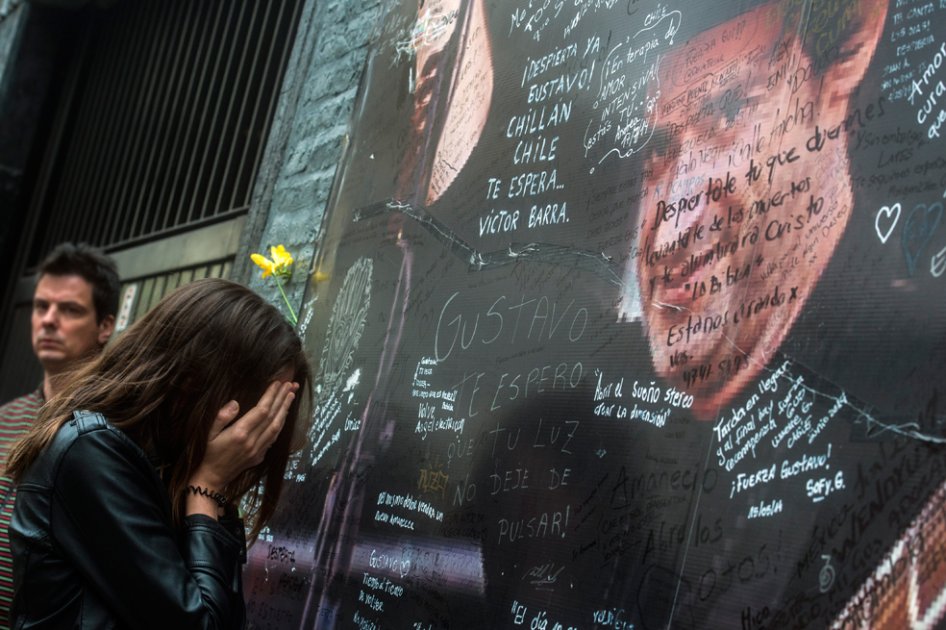 Una fanática del músico argentino Gustavo Cerati escribe un mensaje en un cartel con su imagen afuera de la Clínica ALCLA de Buenos Aires (Argentina).