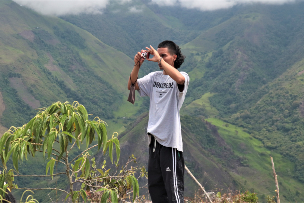 Un hombre está tomando una foto y detrás de él hay una montaña grande.