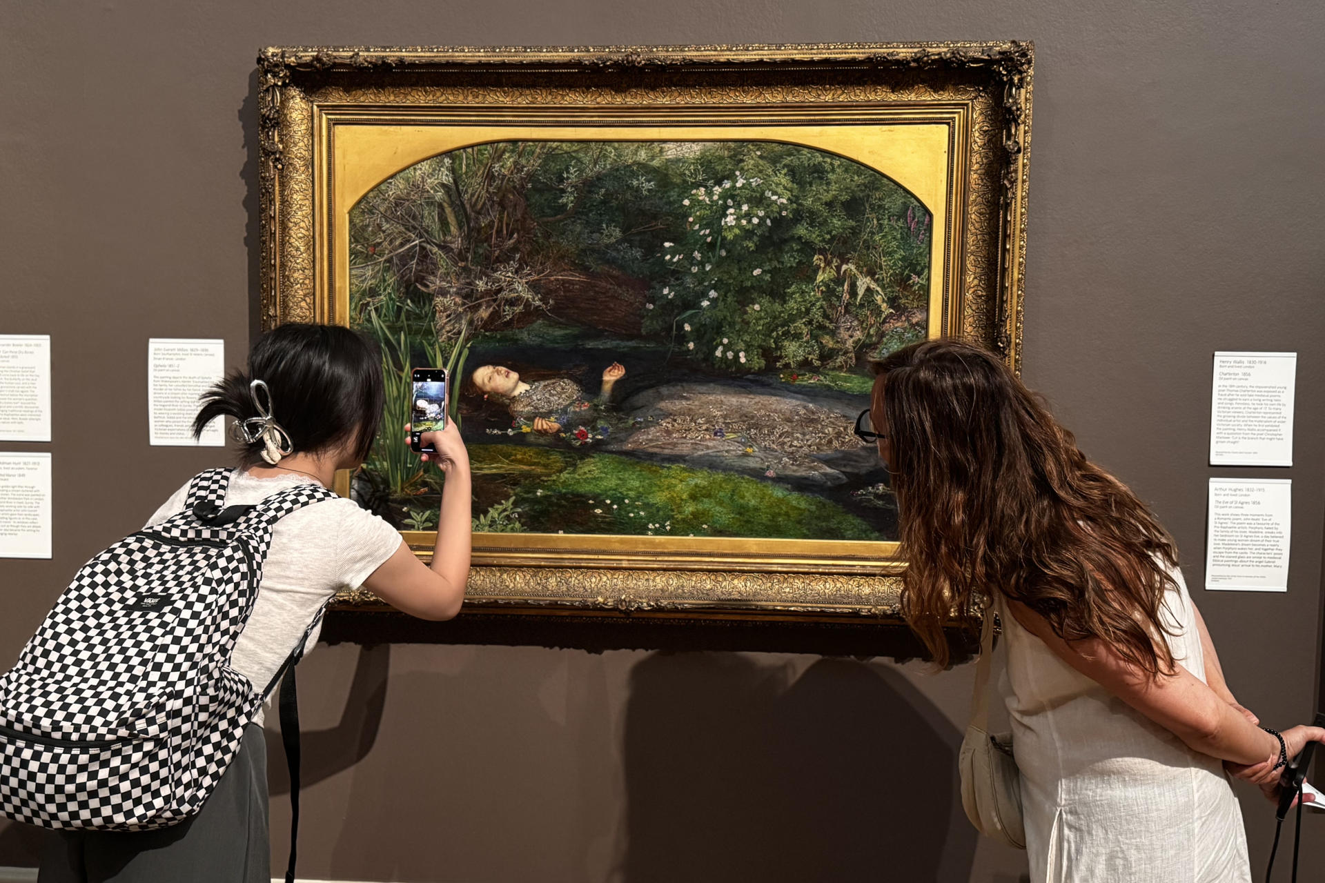 LONDRES, 16/08/2025.- Dos mujeres observan la Ofelia, de John Everett Millais, en la Tate Britain, cuadro en el que se inspira la portada del disco. En 'The Life of a Showgirl', el nuevo álbum de Taylor Swift, la cantante se convierte en Ofelia, personaje del 'Hamlet' de William Shakespeare, recreando en la portada la trágica escena de su muerte, dedicándole uno de los temas y profundizando en su enigmático vínculo creativo con el dramaturgo inglés. EFE/ Raúl Bobé
