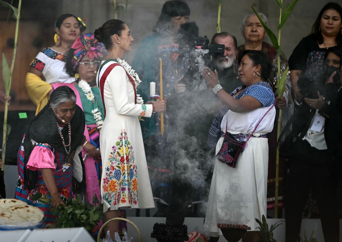 (FILES) Mexico's new President Claudia Sheinbaum (L) takes part in a ceremony in which she receives a ceremonial staff from indigenous people at the Zocalo Square in Mexico City on October 1, 2024.