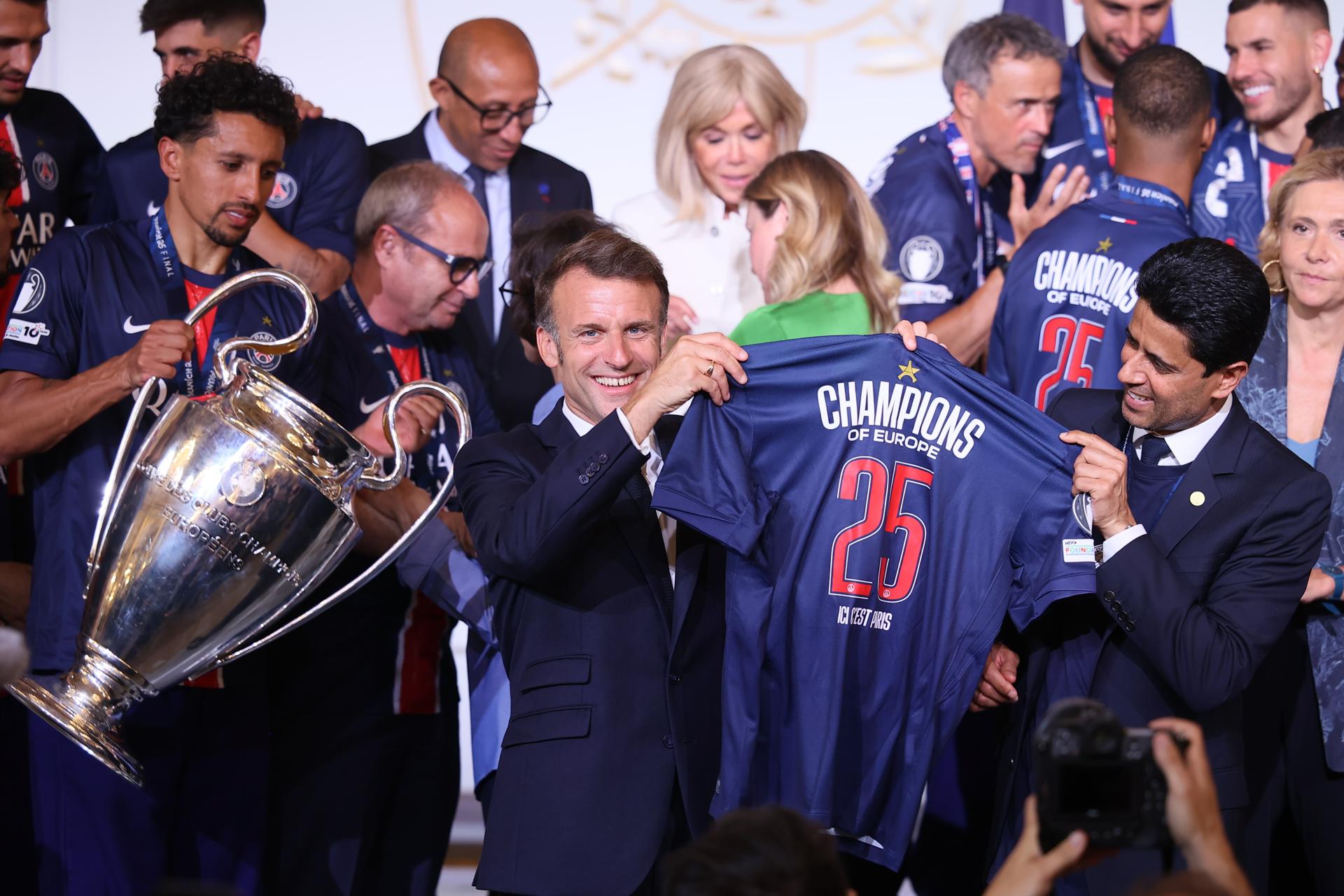 Paris (France), 01/06/2025.- French President Emmanuel Macron (C) holds a PSG jersey “Champions of Europe 2025” with PSG president Nasser Al-Khelaifi (R) while PSG captain Marquinhos (L) carries the trophy during a reception at the Elysee Palace in Paris, France, 01 June 2025. Paris Saint-Germain won the UEFA Champions League for the first time in the club's history after beating Internazionale Milano on 31 May 2025 in the final in Munich. (Liga de Campeones, Francia) EFE/EPA/Thomas Padilla / POOL MAXPPP OUT