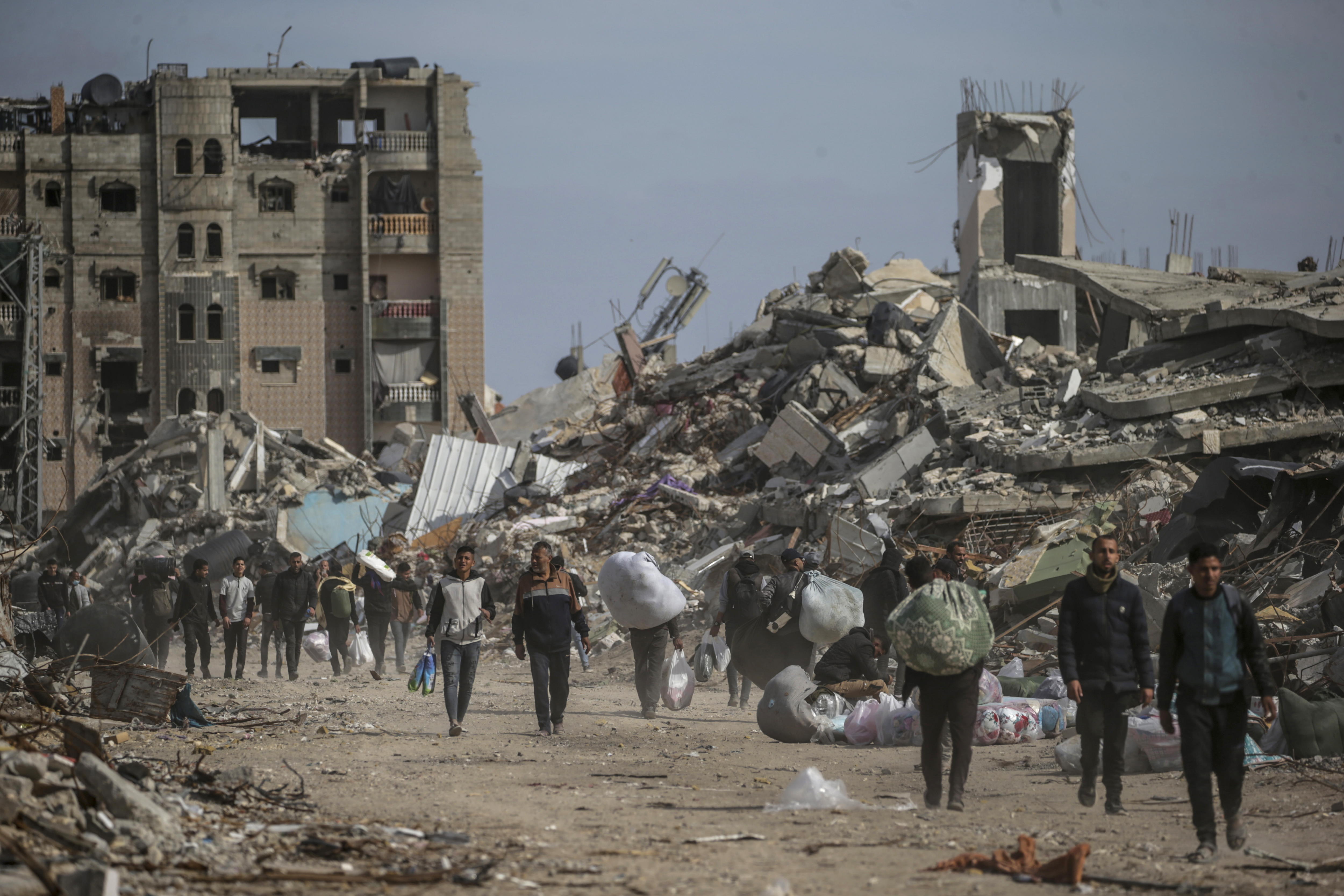 Rafah (-), 19/01/2025.- Internally displaced Palestinians walk near the rubble of destroyed buildings in Rafah, southern Gaza Strip, 19 January 2025, amid a ceasefire between Israel and Hamas. Israel and Hamas agreed on a hostage release deal and a Gaza ceasefire to be implemented on 19 January 2025. More than 46,000 Palestinians have been killed in the Gaza Strip, according to the Palestinian Ministry of Health, since Israel launched a military campaign in the strip in response to a cross-border attack led by the Palestinian militant group Hamas on 07 October 2023, in which about 1,200 Israelis were killed and more than 250 taken hostage. EFE/EPA/MOHAMMED SABER