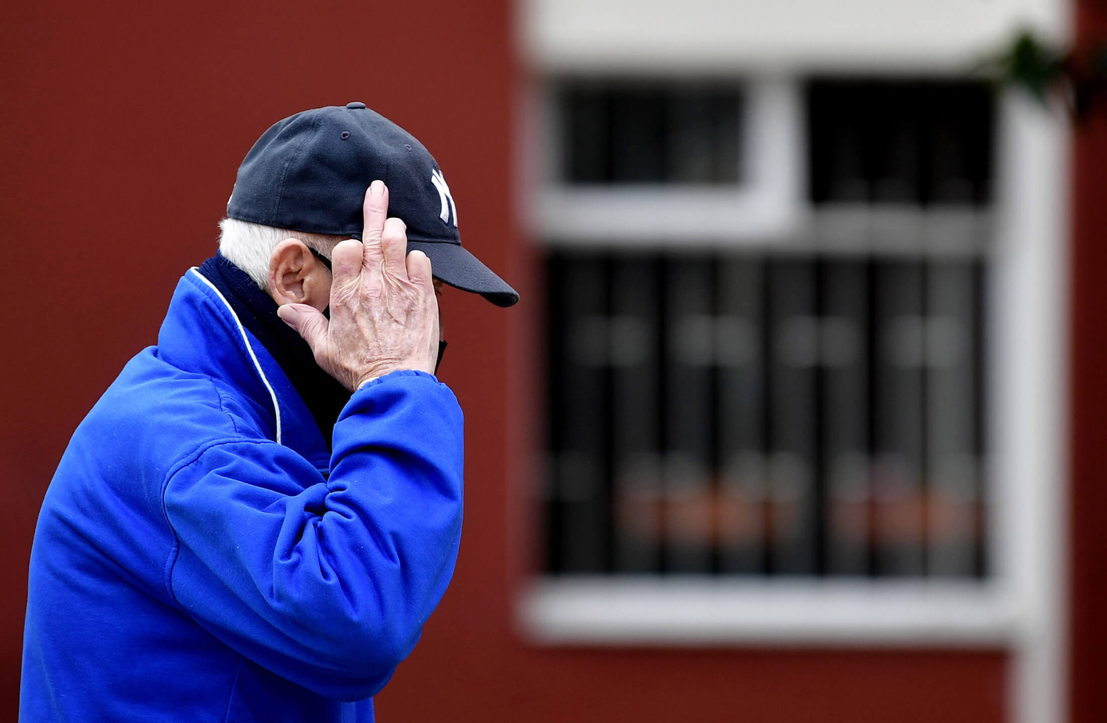 Un anciano en la calle hace un gesto con su mano, durante el aislamiento obligatorio para adultos mayores en Bogotá. / Óscar Pérez