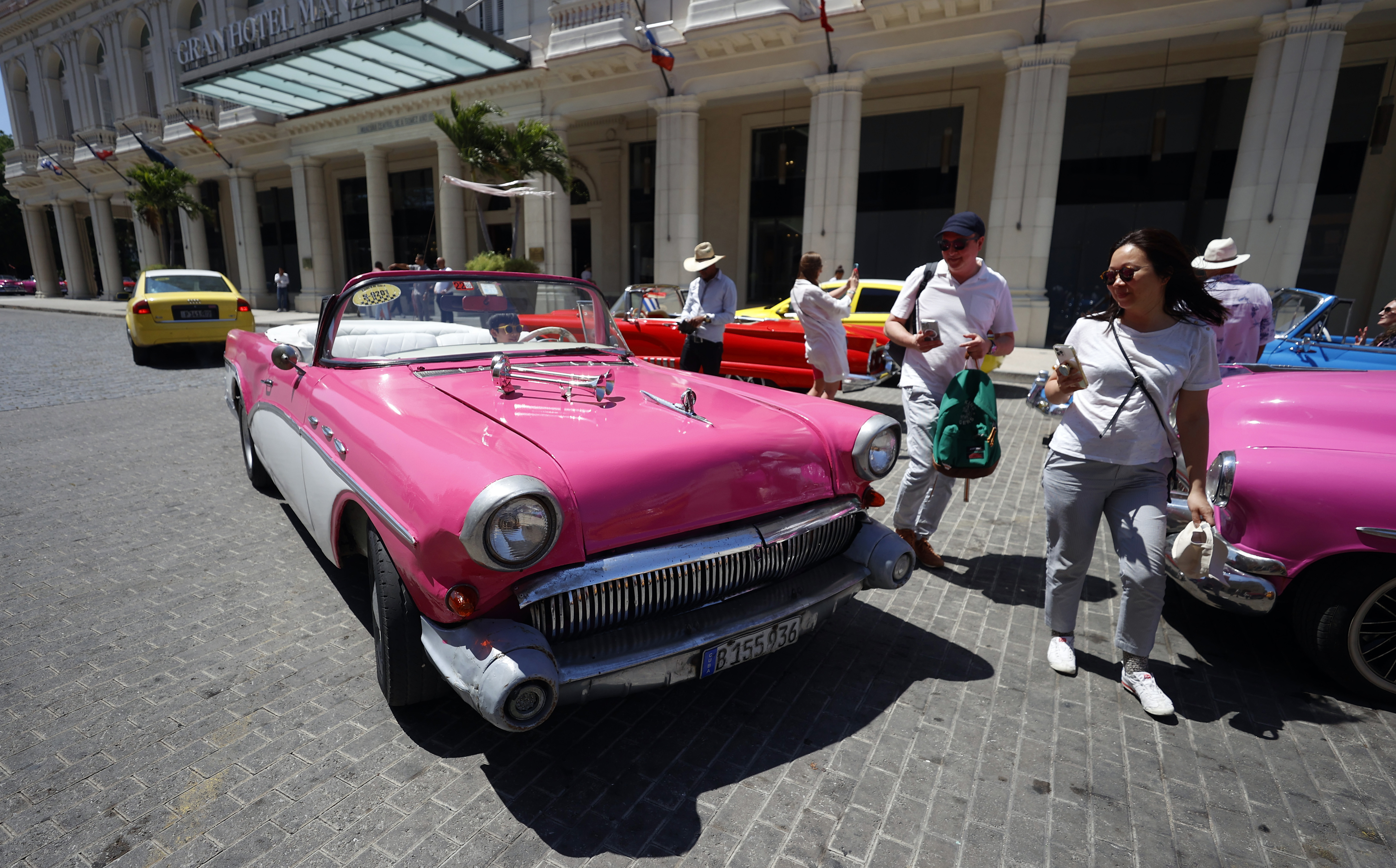 AME1213. LA HABANA (CUBA), 28/04/2024.- Varios turistas toman fotos a autos clásicos, el 22 de abril de 2024, en La Habana (Cuba). El turismo no termina de despegar en Cuba tras la pandemia. Este sector estratégico sigue lastrado por las débiles cifras de visitantes, las sanciones estadounidenses y la profunda crisis que sufre el país, que perjudica al servicio y la experiencia. La celebración del 2 y al 5 de mayo de la Feria Internacional de Turismo (FITCuba), la principal cita del sector en la isla, va a poner de relieve estos retos, las apuestas para 2024 y la dependencia nacional de esta industria, como bosqueja esta radiografía del sector. EFE/ Ernesto Mastrascusa