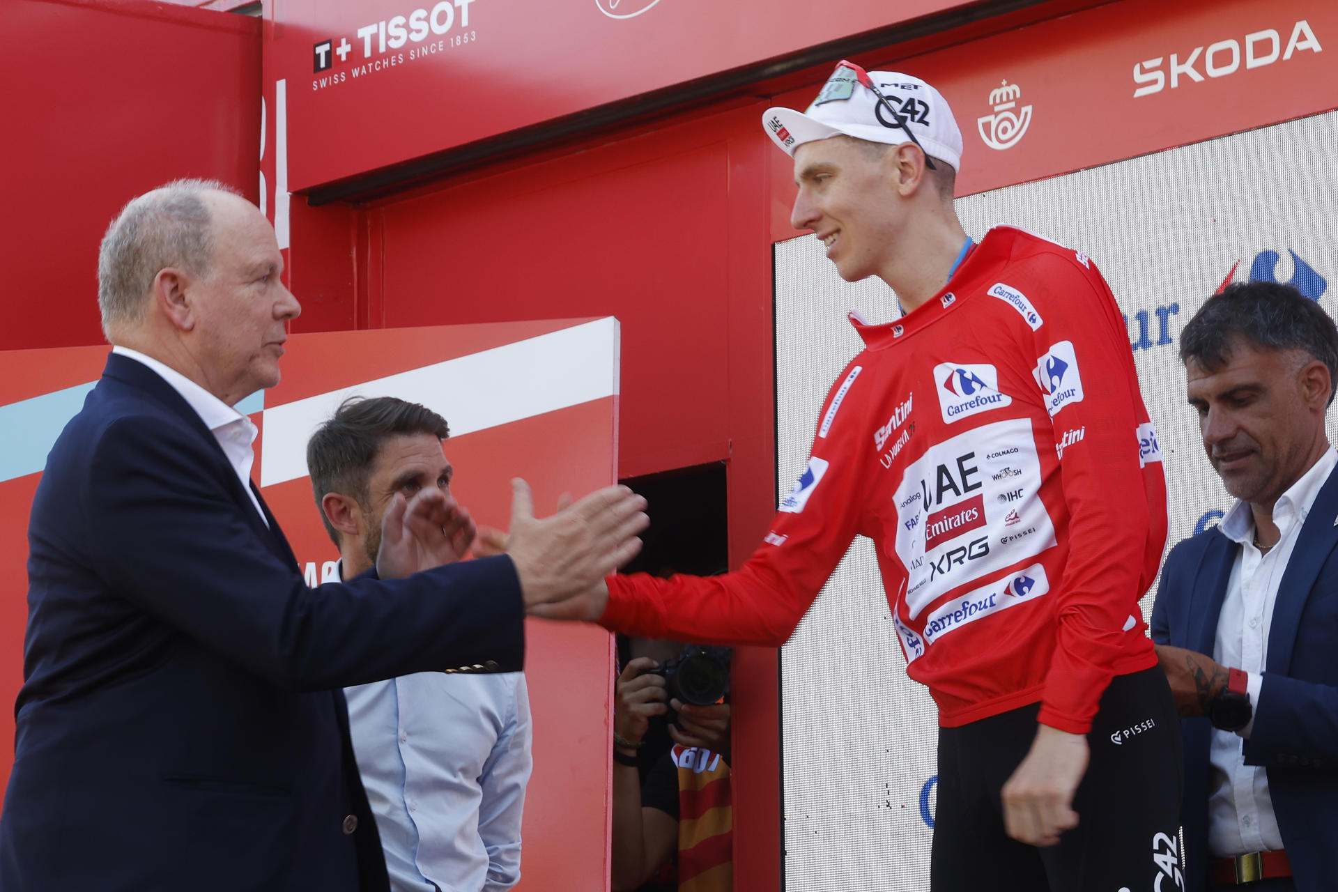MANOSQUE (FRANCIA), 23/08/2026.- El ciclista esloveno Tadej Pogacar, del equipo UAE Team Emirates XRG, es felicitado por el príncipe Alberto II de Mónaco en el podio tras convertirse en líder de la clasificación general tras la segunda etapa de la Vuelta disputada este domingo entre la capital del Principado y la localidad francesa de Manosque, con un recorrido de 214,3 km, la más larga de la presente edición. EFE/ Javier Lizón
