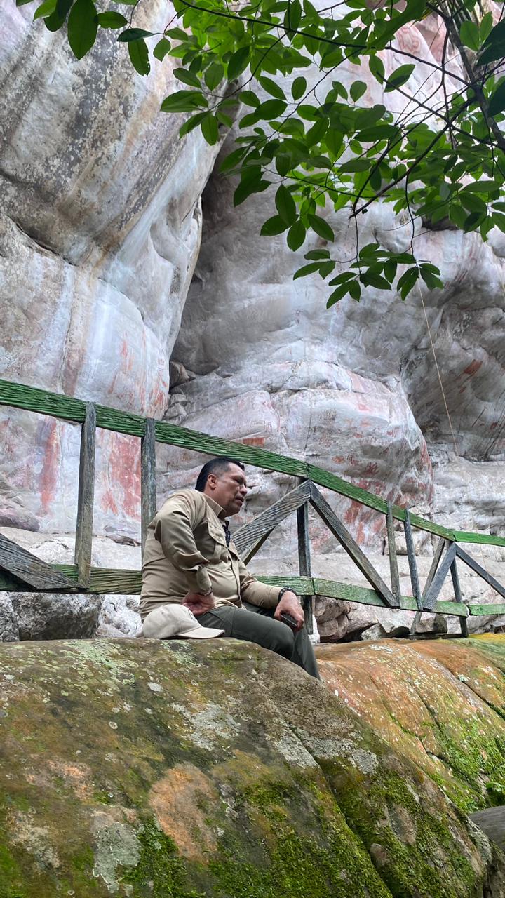 Norbey Méndez sentado detrás de los macizos con arte rupestre en Raudal del Guayabero.