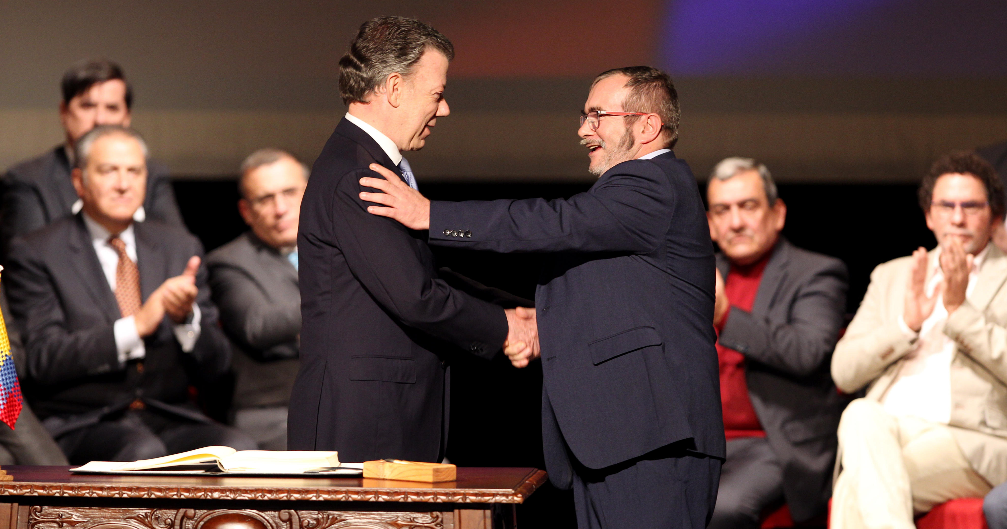 BOG104. BOGOTÁ (COLOMBIA), 24/11/2016.- El presidente de Colombia Juan Manuel Santos (i) y el jefe máximo de las FARC Rodrigo Londoño Echeverry (d) se felicitan luego de firmar el nuevo acuerdo de paz para terminar 52 años de conflicto armado interno hoy, jueves 24 de noviembre de 2016, en Bogotá (Colombia). Santos y "Timochenko" firmaron el acuerdo, que complementa el original del pasado 26 de septiembre en Cartagena de Indias, a las 11.30 hora local (16.30 GMT) en el Teatro Colón de Bogotá. Primero lo hizo el jefe guerrillero y luego el jefe de Estado, quienes utilizaron, al igual que en el primer acuerdo, un "balígrafo", bolígrafo fabricado con un casquillo de bala de fusil, que simboliza el tránsito de Colombia de la guerra a la paz. EFE/MAURICIO DUENAS CASTAÑEDA