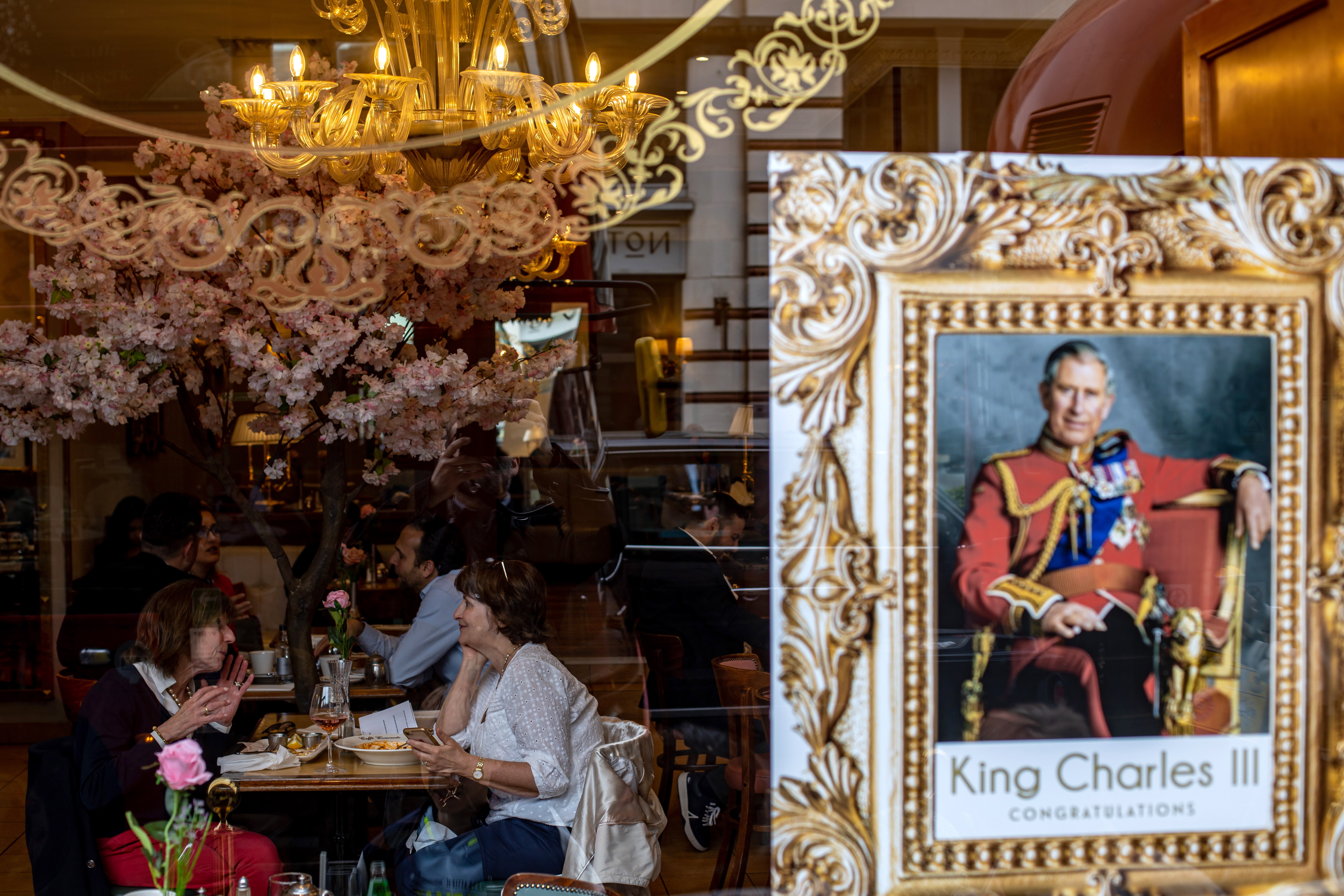 London (United Kingdom), 04/05/2023.- People talk as a portrait of King Charles III is placed on a cafe window in London, Britain, 04 May 2023. Britain's King Charles III's Coronation takes place at Westminster Abbey on 06 May 2023. (Reino Unido, Londres) EFE/EPA/MARTIN DIVISEK