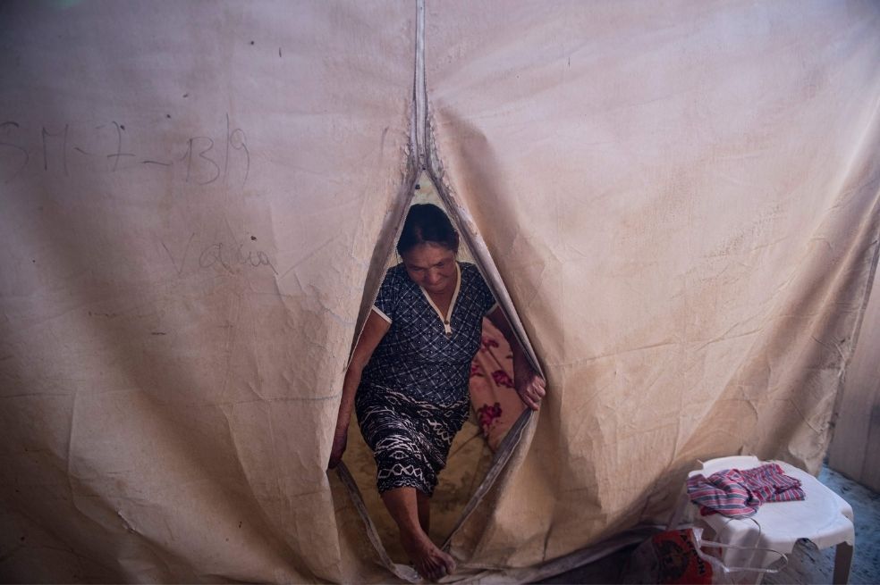 Una mujer limpia su habitación construida dentro de una carpa instalada en 2017 por la Defensa Civil en su casa en el "Refugio San Pablo", un campamento de casas precarias de paja y carpas al norte de Lima.