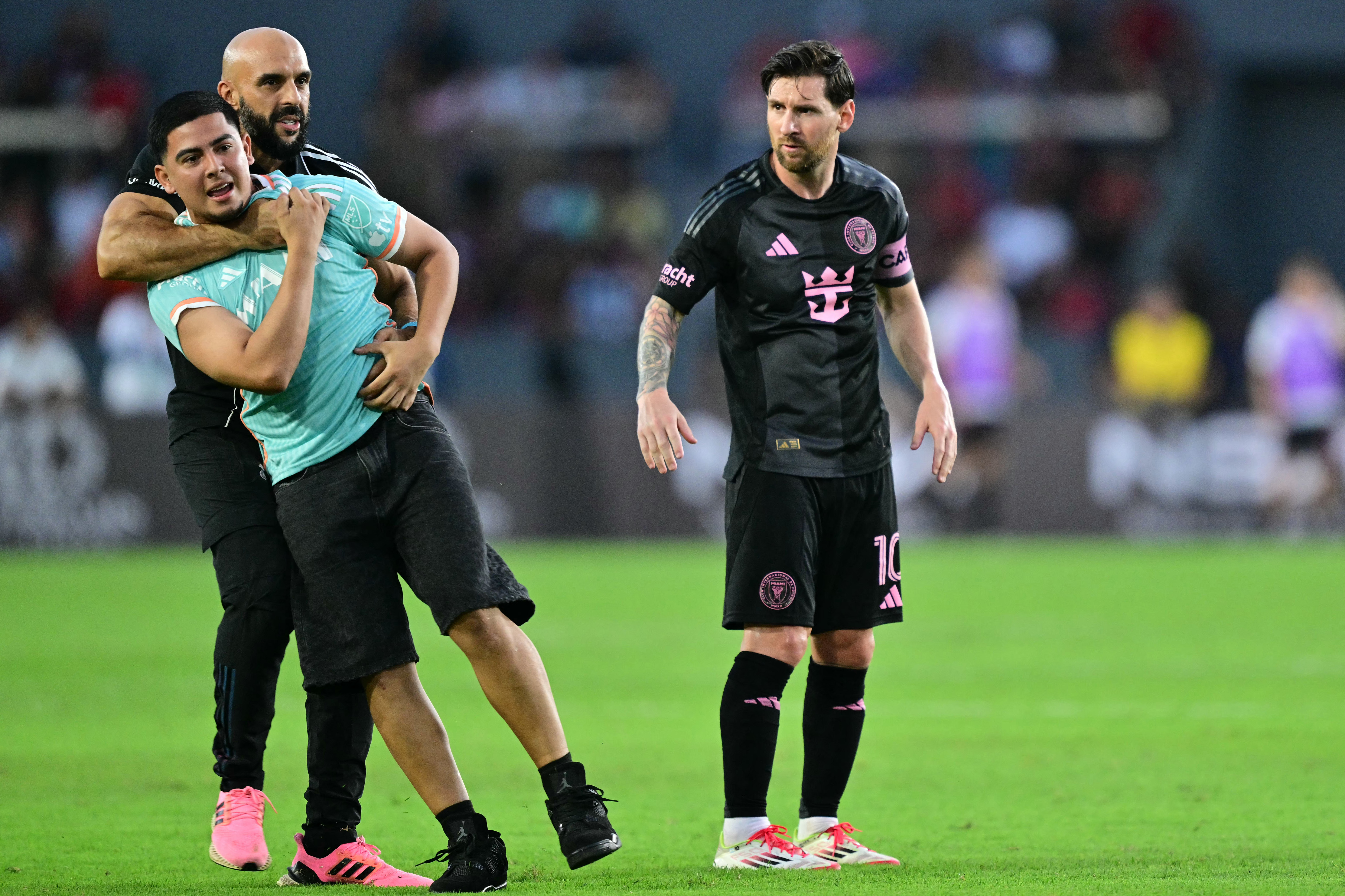 Un aficionado es escoltado fuera del campo por un asistente después de abrazar al delantero argentino #10 del Inter de Miami, Lionel Messi, durante el partido amistoso de fútbol entre el Sporting San Miguelito de Panamá y el Inter de Miami de EE. UU. en el estadio Romeo Fernández en la Ciudad de Panamá el 2 de febrero de 2025.