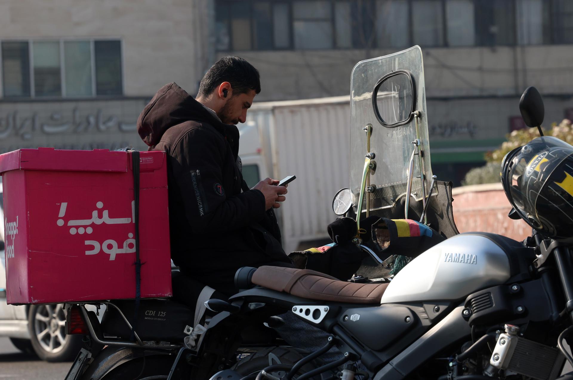 TEHRAN (IRAN(Islamic Republic Of)), 27/01/2026.- An Iranian man checks his phone on a street in Tehran, Iran, 27 January 2026. Iran is experiencing a nationwide internet blackout that began on 08 January 2026 amid an intensifying wave of anti-government protests. (Protestas, Teherán) EFE/EPA/ABEDIN TAHERKENAREH
