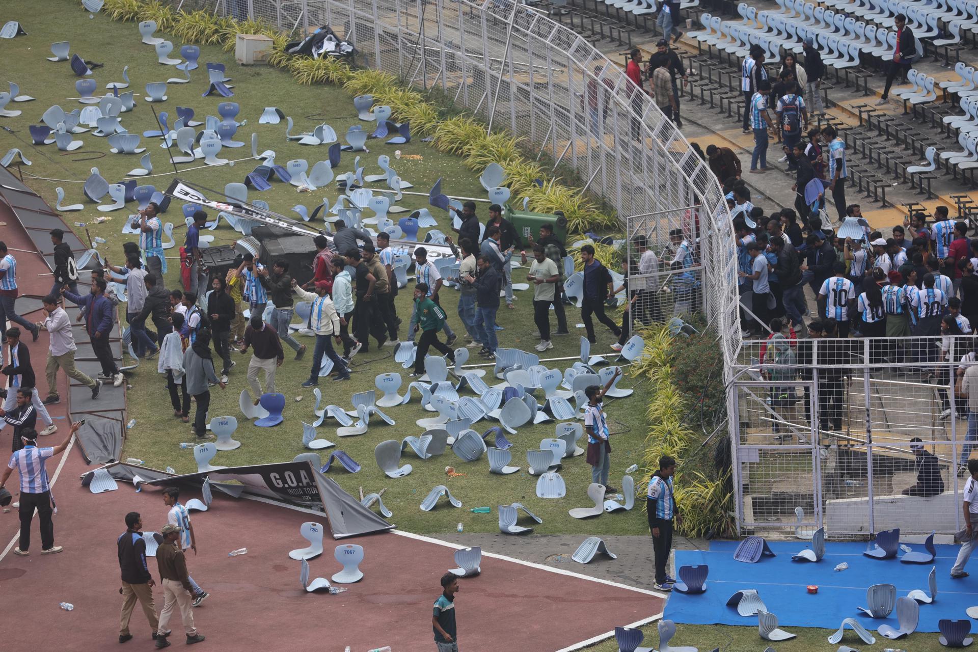 FOTODELDÍA CALCUTA (INDIA), 13/12/2025.- Aficionados lanzan botellas, sillas y vandalizan vallas publicitarias en el estadio Salt Lake de Calcuta, Bengala Occidental, India, este sábado. Las fuerzas de seguridad de la India realizaron cargas policiales este sábado contra grupos de aficionados en Calcuta tras estallar disturbios generalizados por la brevedad de la visita del futbolista Lionel Messi, cuya aparición en el estadio duró apenas 22 minutos y fue calificada de "estafa" por los asistentes. EFE/ Piyal Adhikary

