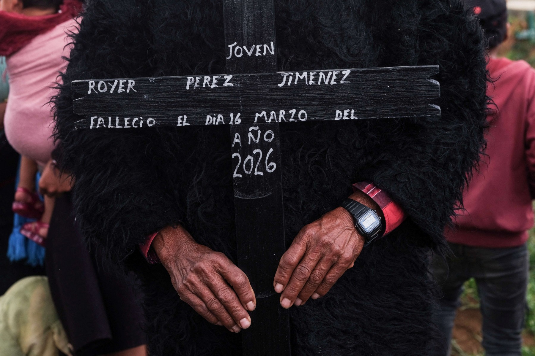 A man holds a cross bearing the name of Royer Perez Jimenez, a 19-year-old Mexican migrant who was found dead in a US detention center, during his funeral in the Tzotzil indigenous community of San Juan Chamula, Chiapas state, Mexico on April 4, 2026.