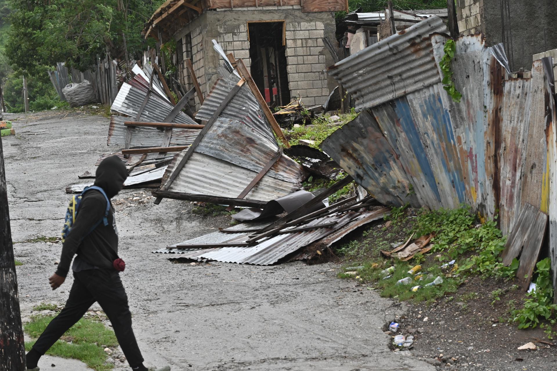 USA5818. KINGSTON (JAMAICA), 28/10/2025.- Una persona camina frente a una casa afectada por el paso del huracán Melissa este martes, en Kingston (Jamaica). El potente huracán Melissa tocó tierra en Jamaica con vientos máximos sostenidos cercanos a los 295 kilómetros por hora (185 millas), lluvias torrenciales y marejadas que amenazan con provocar inundaciones y daños catastróficos. EFE/Rudolph Brown