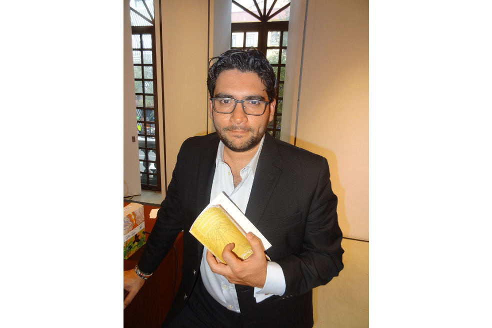 Rolando Kattan tiene en sus manos un libro con la portada color amarillo.