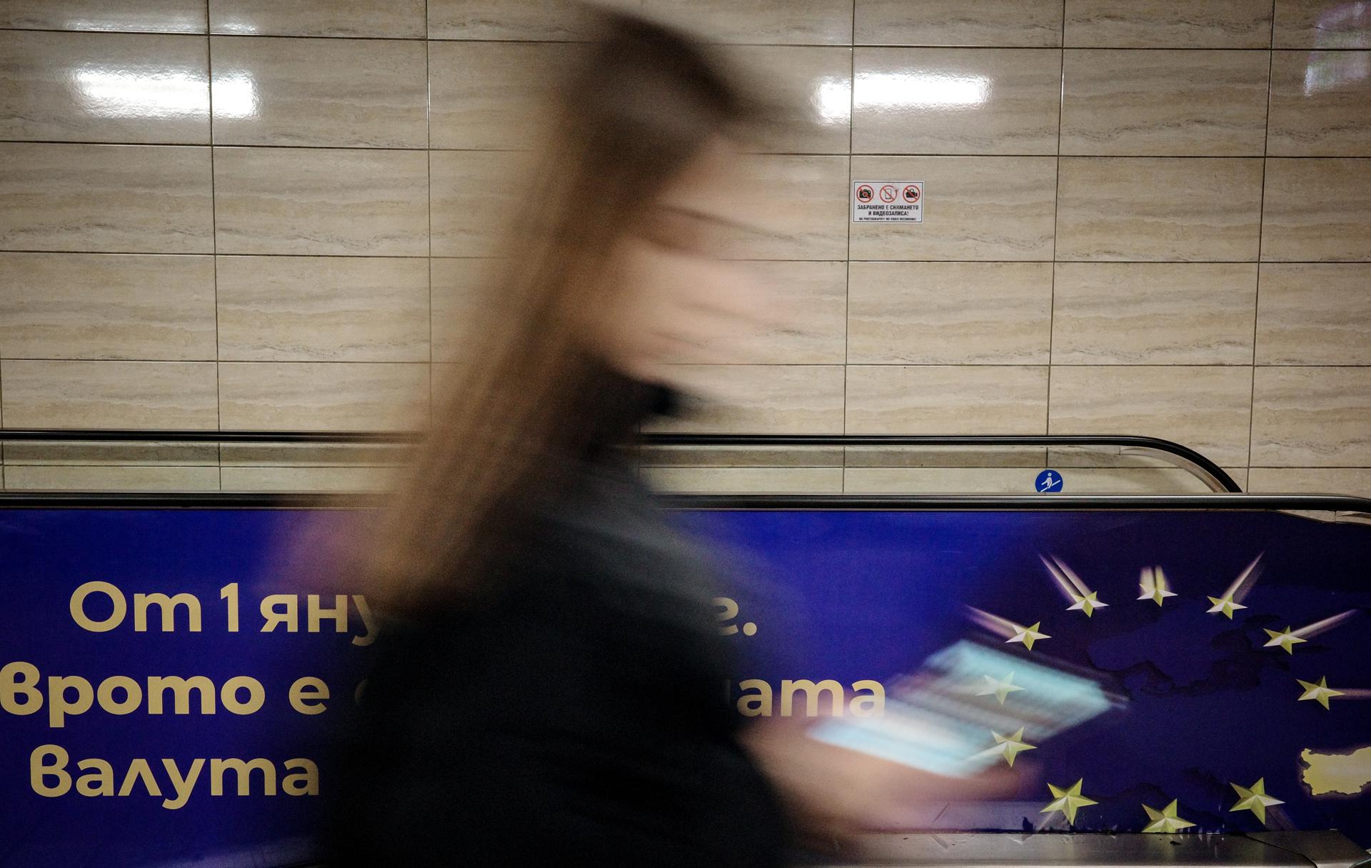 SOFIA (Bulgaria), 29/12/2025.- A slow-shutter photo shows a woman passing a euro adoption poster in Sofia, Bulgaria, 29 December 2025. Bulgaria is set to become the 21st member of the eurozone on 01 January 2026, transitioning from the national lev to the euro amid public concerns that the move could trigger immediate price hikes and a higher cost of living. EFE/EPA/BORISLAV TROSHEV
