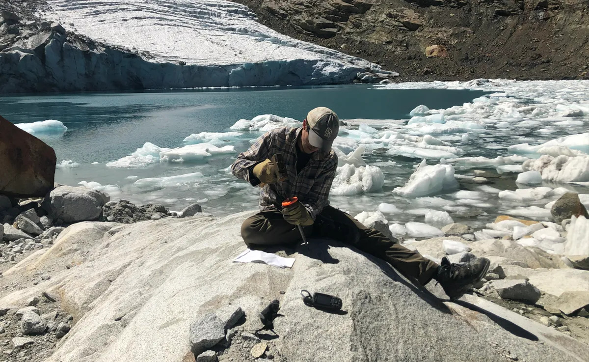 Un científico toma una muestra de roca del glaciar Queshque en la cordillera de los Andes en Perú.
