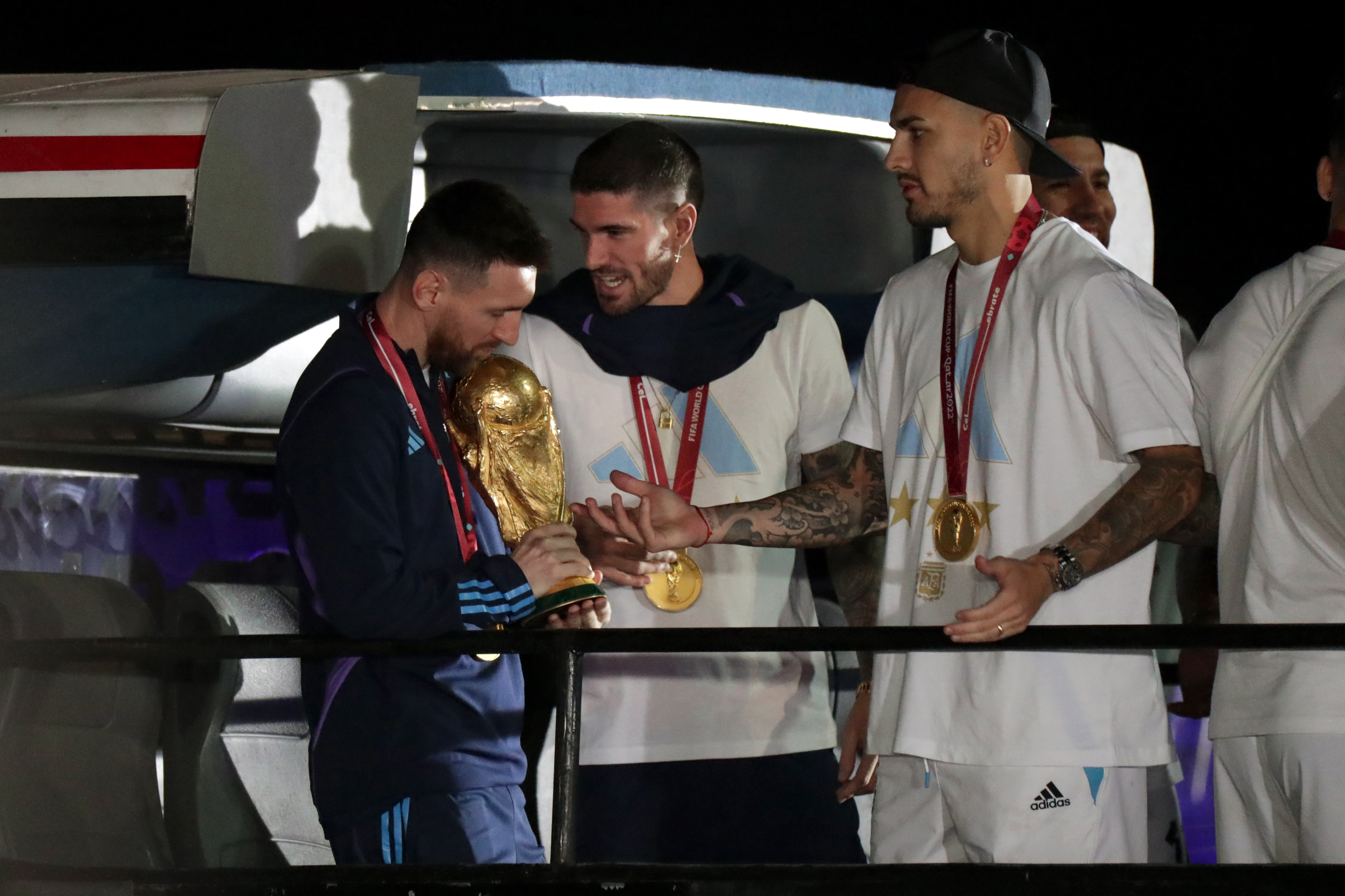 AMDEP9828. EZEIZA (ARGENTINA), 19/12/2022.- Lionel Messi (i) de la selección argentina de fútbol observa el trofeo del Mundial de Fútbol Qatar 2022 junto a Rodrigo de Paul (c) a su llegada hoy, al Aeropuerto Internacional de Ezeiza a unos 22km de Buenos Aires (Argentina). EFE/ Raúl Martínez