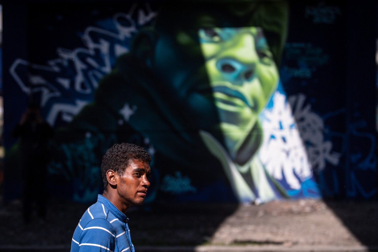 Un hombre de perfil camina frente a un grafiti