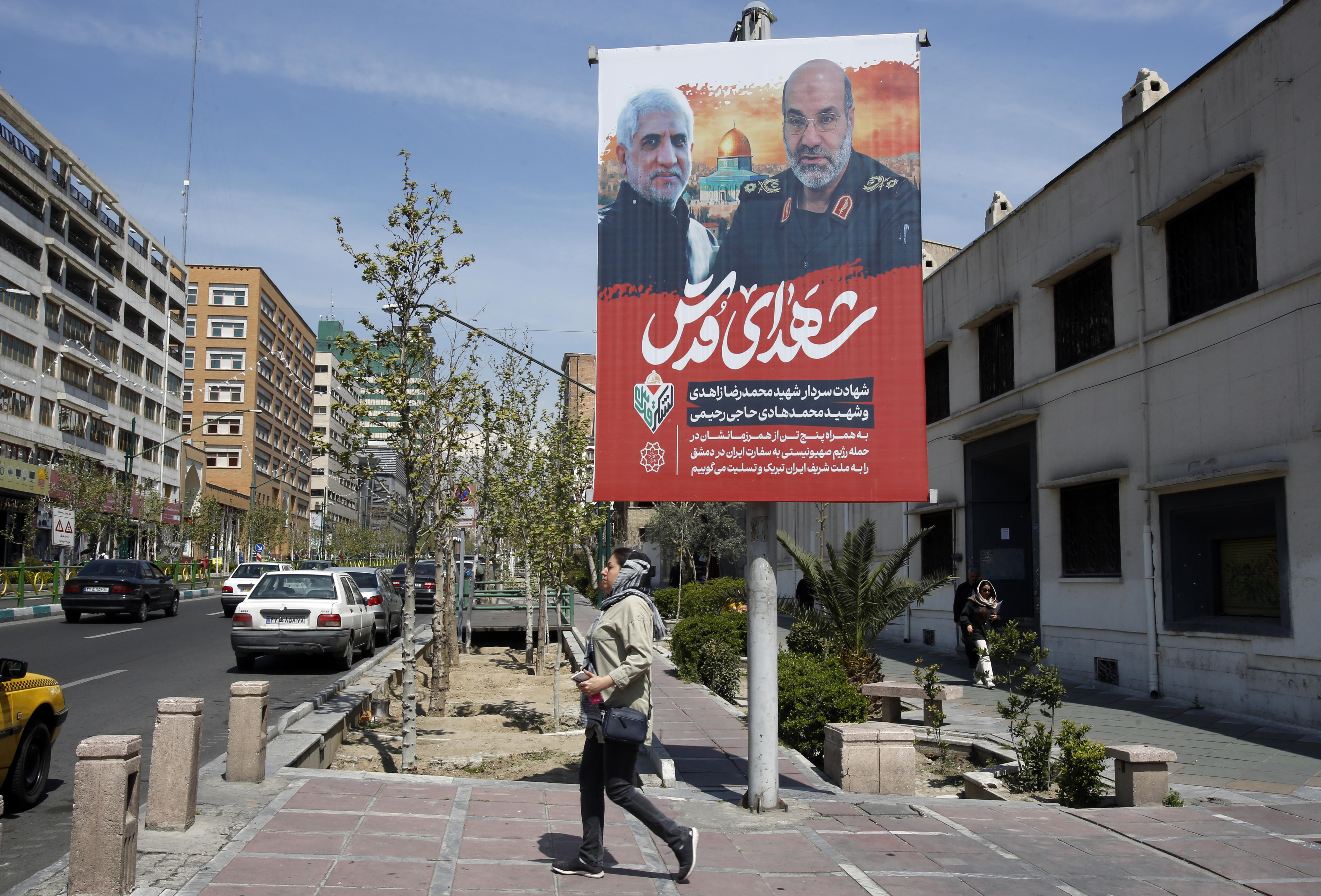 Tehran (Iran (islamic Republic Of)), 03/04/2024.- A woman walks past a billboard displaying pictures of Iranian Brigadier General Mohammad Reza Zahedi (R), a commander of the Islamic Revolutionary Guard Corps (IRGC)'s Quds Force, and his deputy General Mohammad Hadi Haji Rahimi (L), at a street in Tehran, Iran, 03 April 2024. According to Iranian state media quoting the Islamic Revolutionary Guard Corps, at least seven IRGC military advisors, including generals Mohammad Reza Zahedi and Mohammad Hadi Haj Rahimi, were killed in an airstrike on the Iranian consulate building in Syria's capital Damascus on 01 April. Iran has blamed Israel for the attack and vowed to respond. (Protestas, Siria, Damasco, Teherán) EFE/EPA/ABEDIN TAHERKENAREH