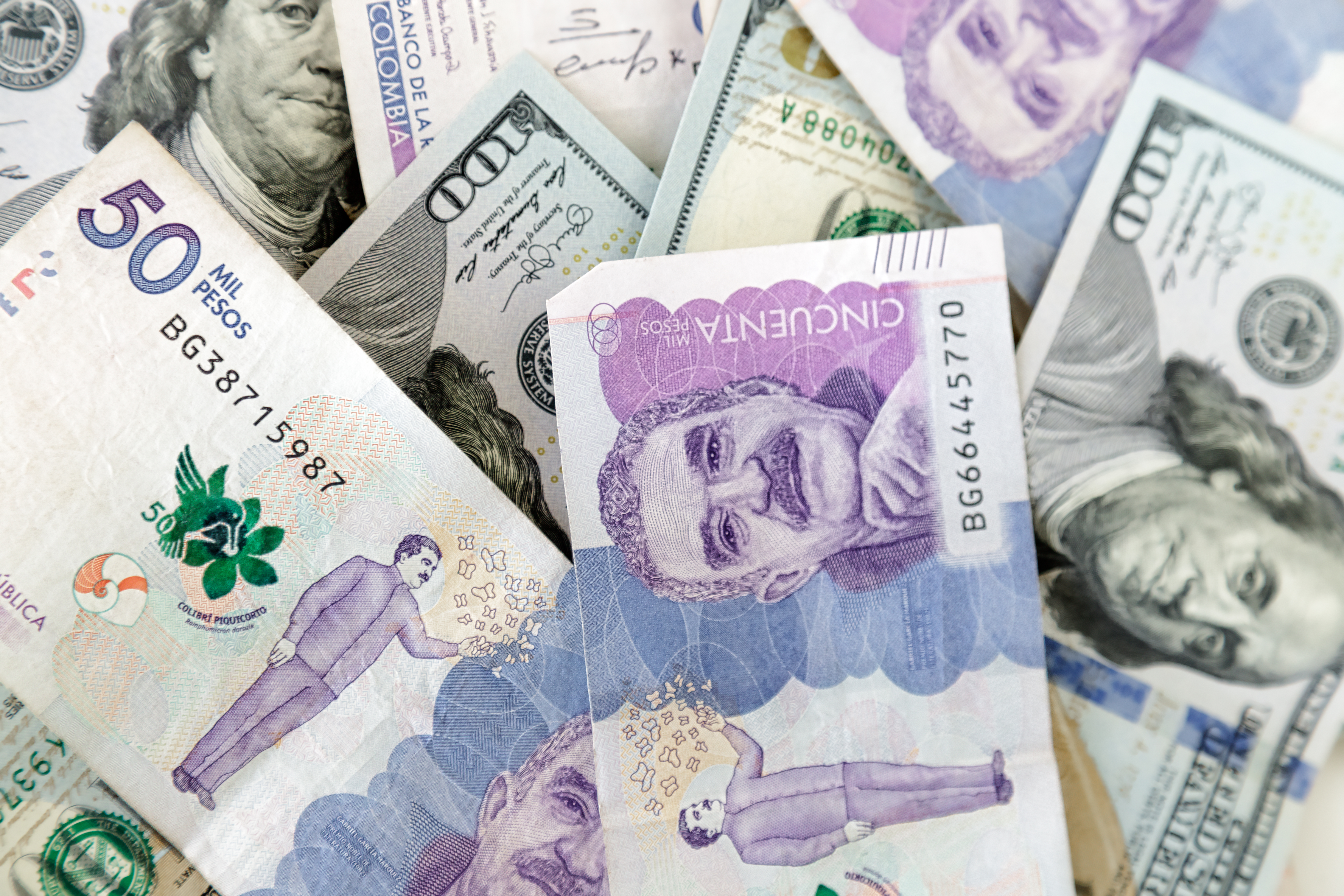 Imagen de billetes de dólares estadounidenses y pesos colombianos.